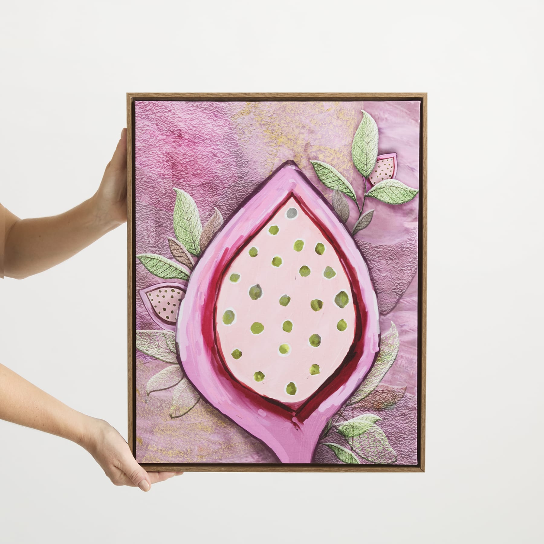 Ein gerahmtes Kunstwerk mit einem großen, rosafarbenen, tropfenförmigen Objekt mit goldenen Punkten, umgeben von grünen Blättern vor einem leuchtend violetten und rosafarbenen Hintergrund.