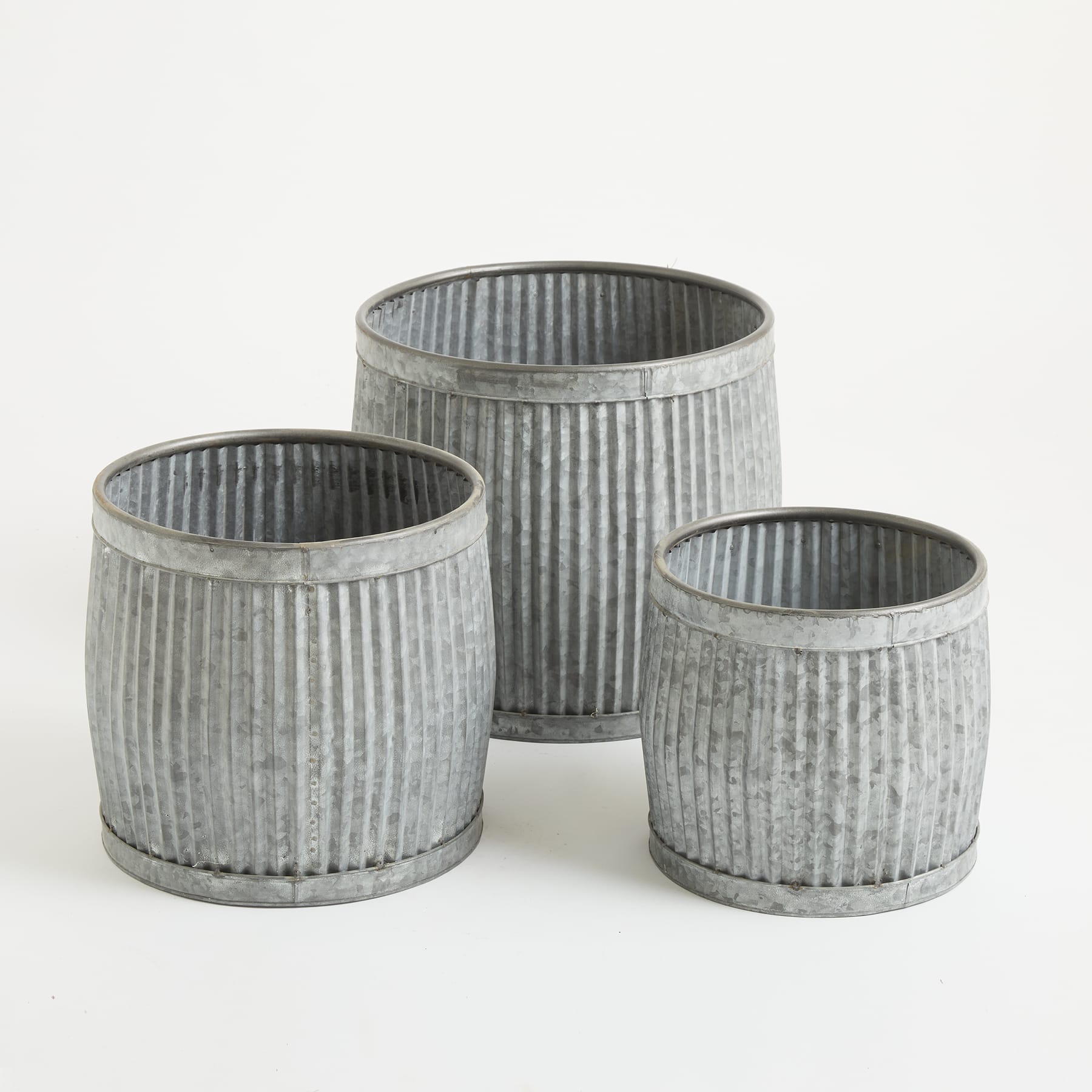 Drei zylindrische Metallbehälter mit gerippter Textur, in einer Gruppe auf einem schlichten Hintergrund angeordnet.