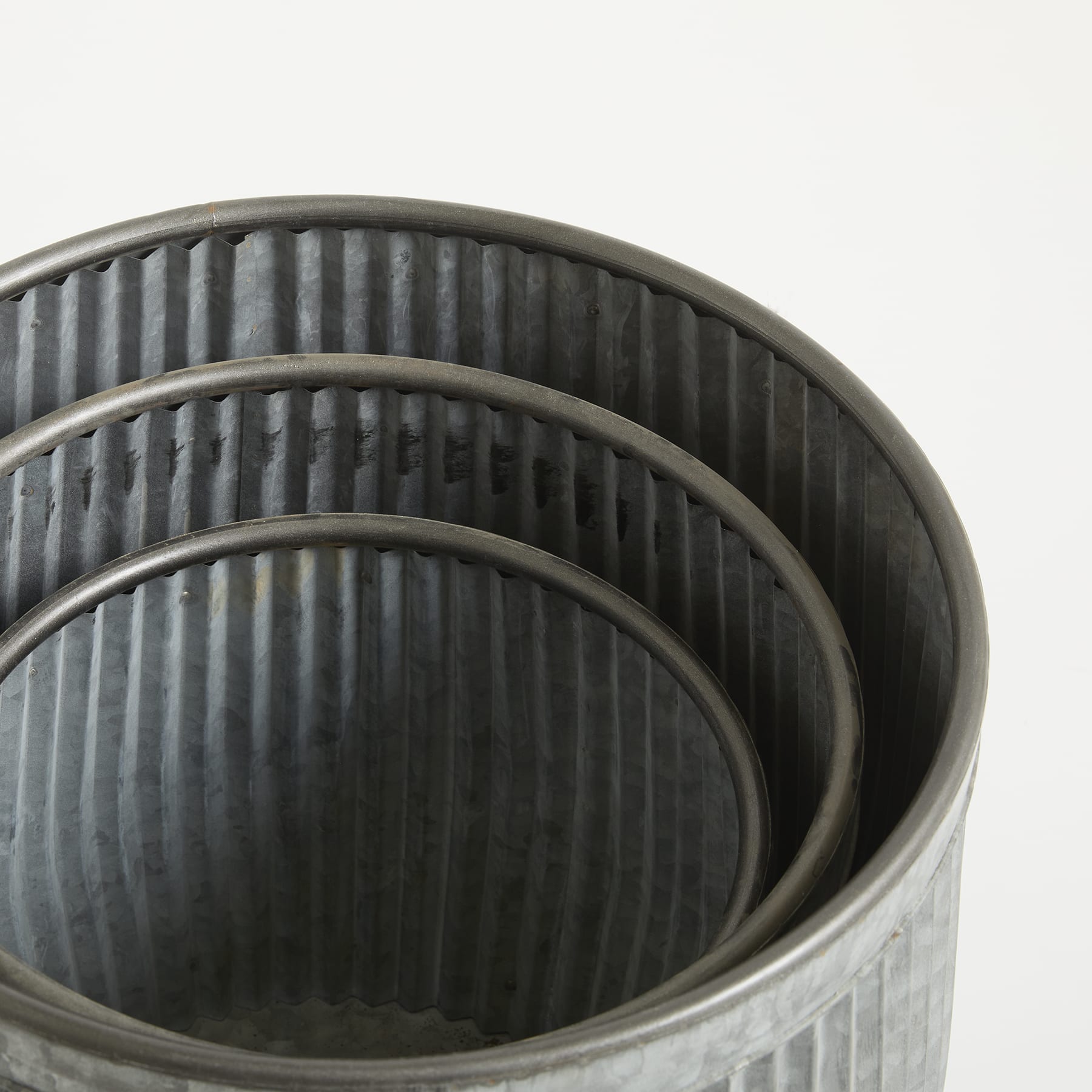 Das Bild zeigt drei ineinander verschachtelte Metallbehälter mit vertikalen Rippen, die eine optisch interessante und strukturierte Komposition ergeben.