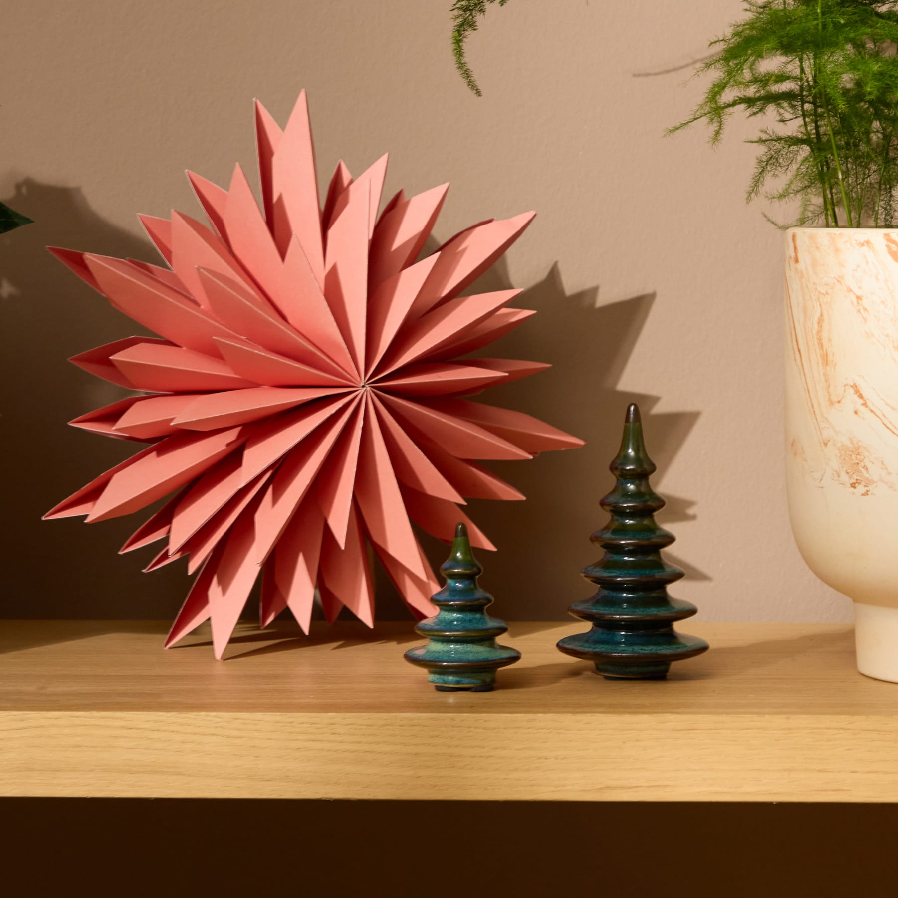 Vor einem schlichten weißen Hintergrund stehen zwei keramische Dekorationsobjekte, die stilisierten Weihnachtsbäumen ähneln und eine grüne und blaue Glasur aufweisen.