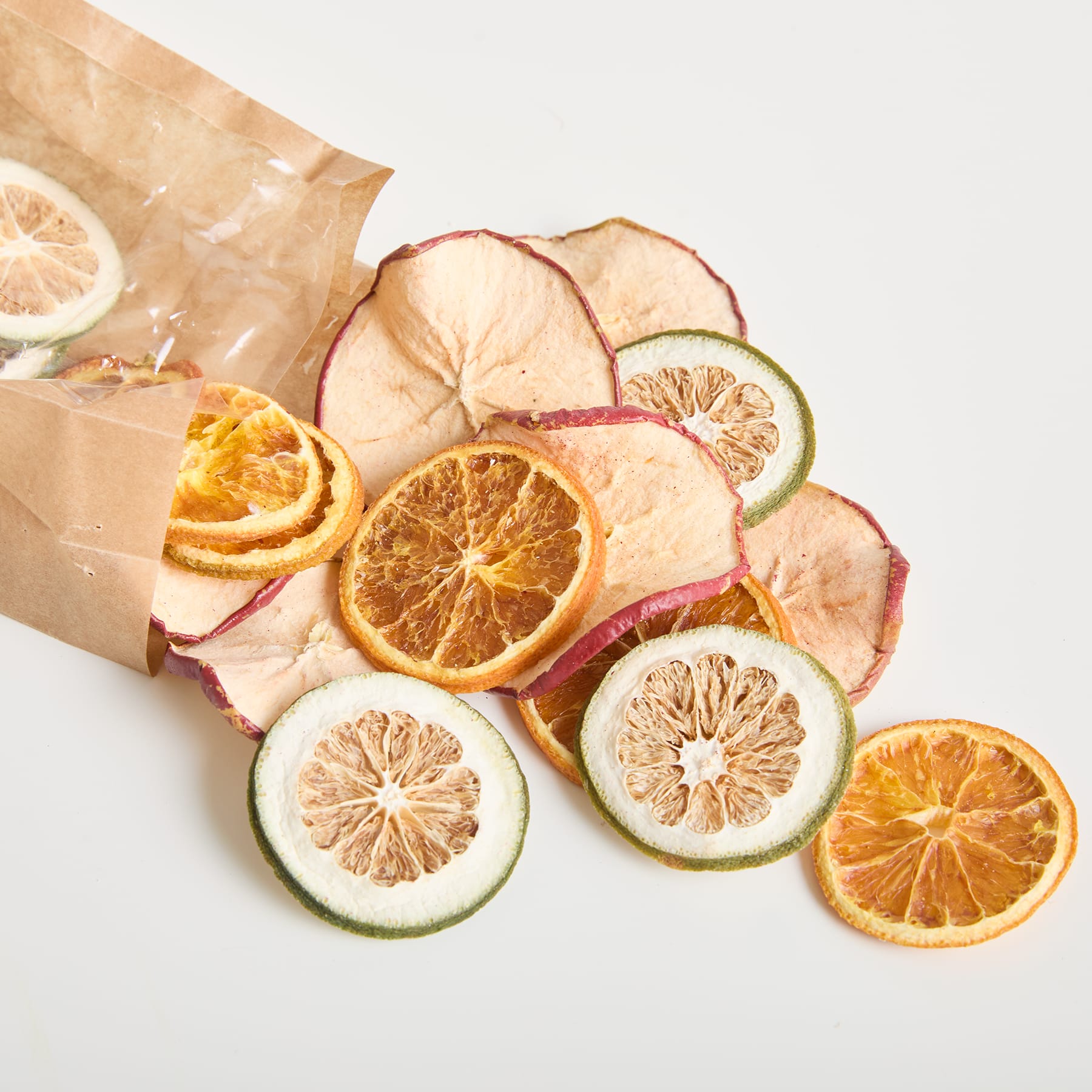 Eine Papiertüte gefüllt mit verschiedenen geschnittenen Zitrusfrüchten, darunter Zitronen, Limetten und Orangen, angeordnet auf einem weißen Hintergrund.