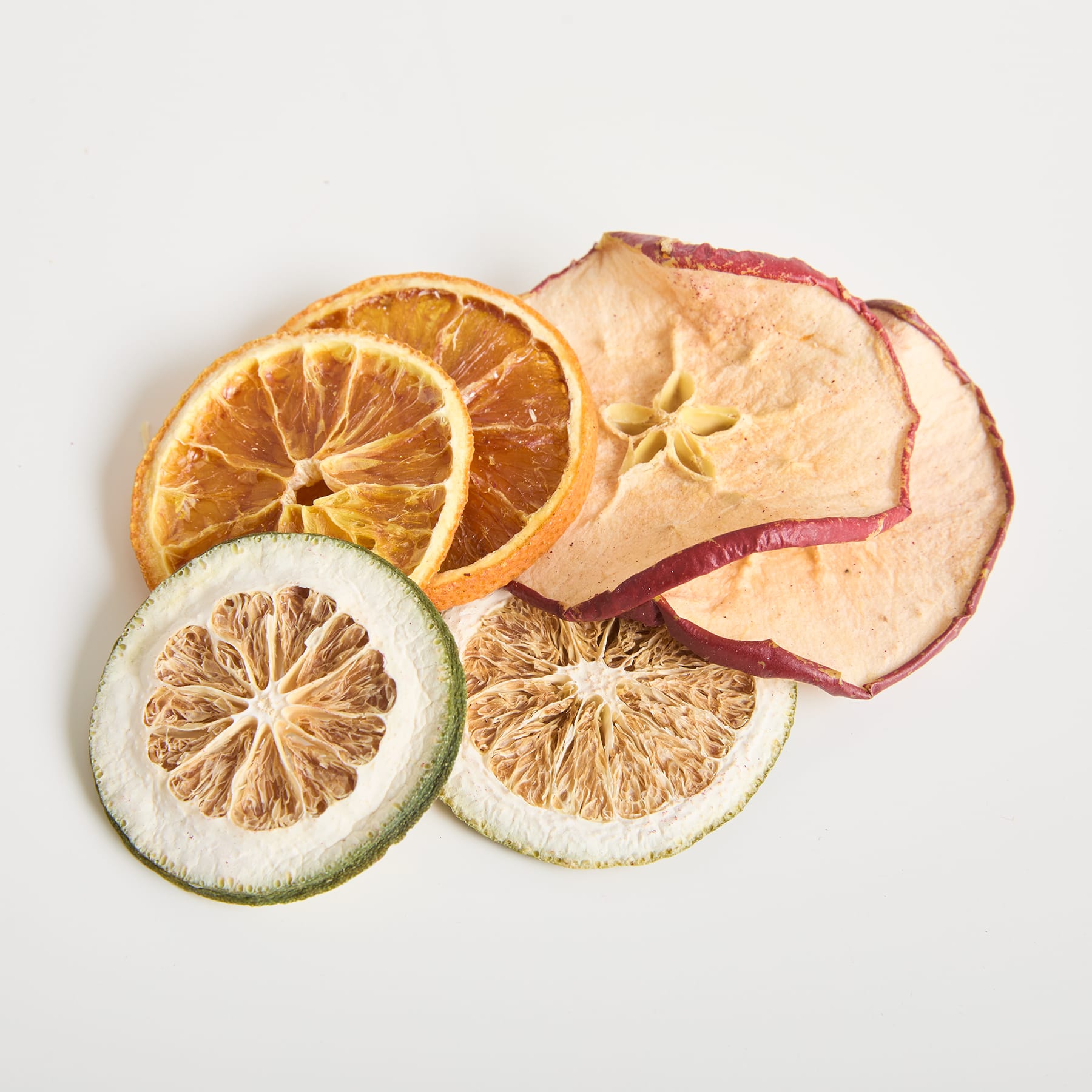 Aufgeschnittene Zitrusfrüchte, darunter Orangen, Zitronen und getrocknete Äpfel oder Birnen, angeordnet auf einem schlichten weißen Hintergrund.