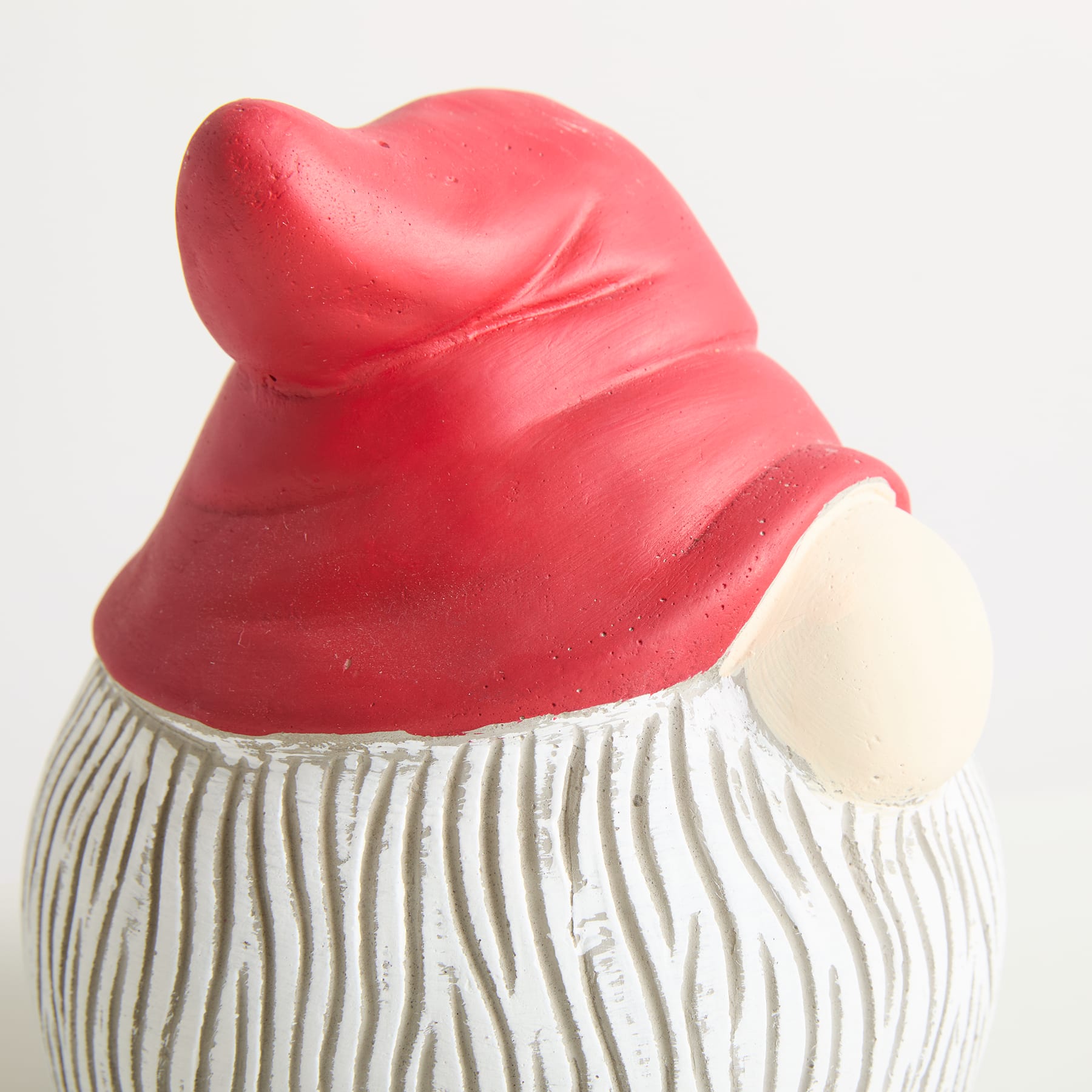 Eine leuchtend rote, gnomenartige Figur mit einem gestreiften weiß-grauen Körper steht vor einem schlichten weißen Hintergrund.