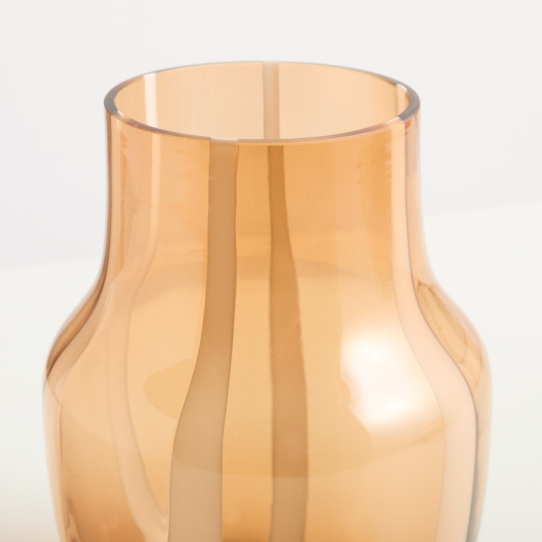Eine durchscheinende, bernsteinfarbene Glasvase mit einer ausgestellten, glockenförmigen Form steht vor einem schlichten weißen Hintergrund.