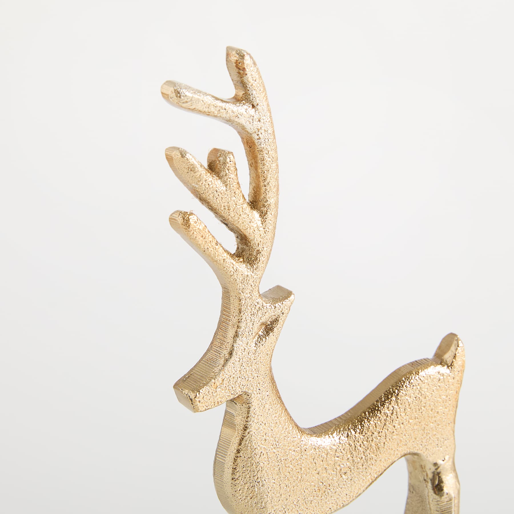 Eine goldene, metallische, hirschähnliche Figur steht vor einem schlichten weißen Hintergrund.