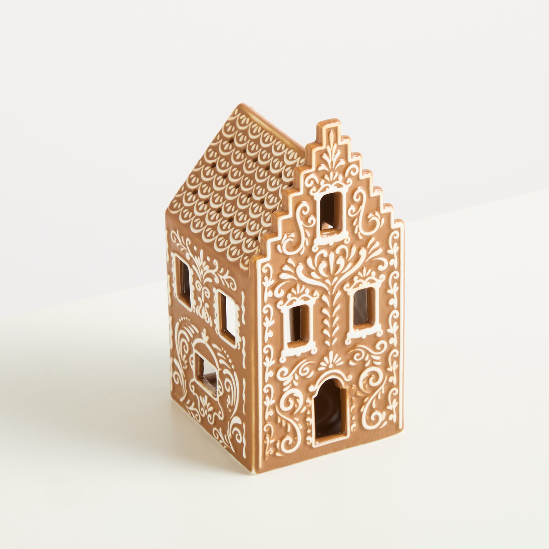 Ein dekoratives Lebkuchenhaus mit komplizierten Mustern und Designs vor einem schlichten Hintergrund.