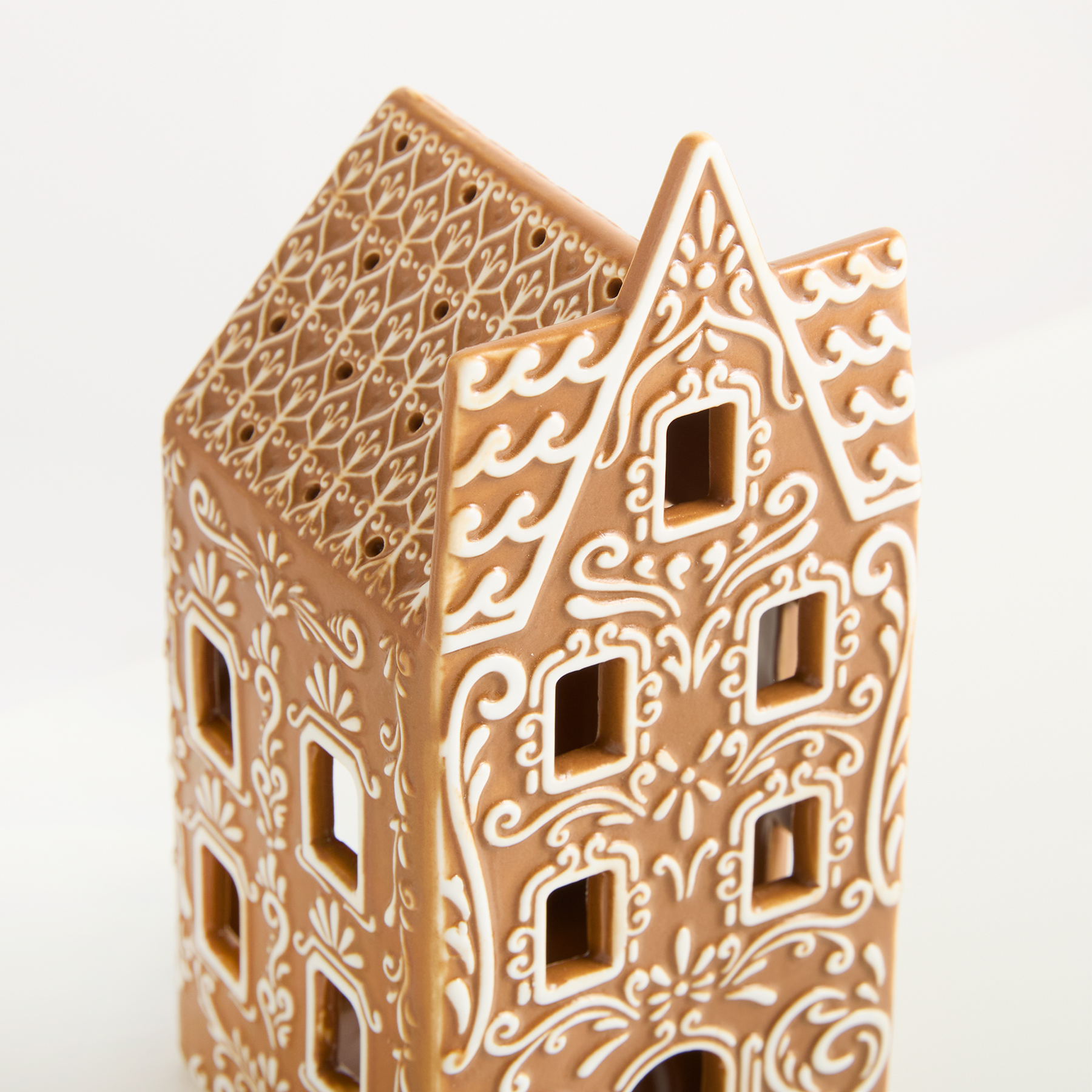 Ein dekoratives Lebkuchenhaus mit komplizierten Mustern und Designs vor einem schlichten weißen Hintergrund.