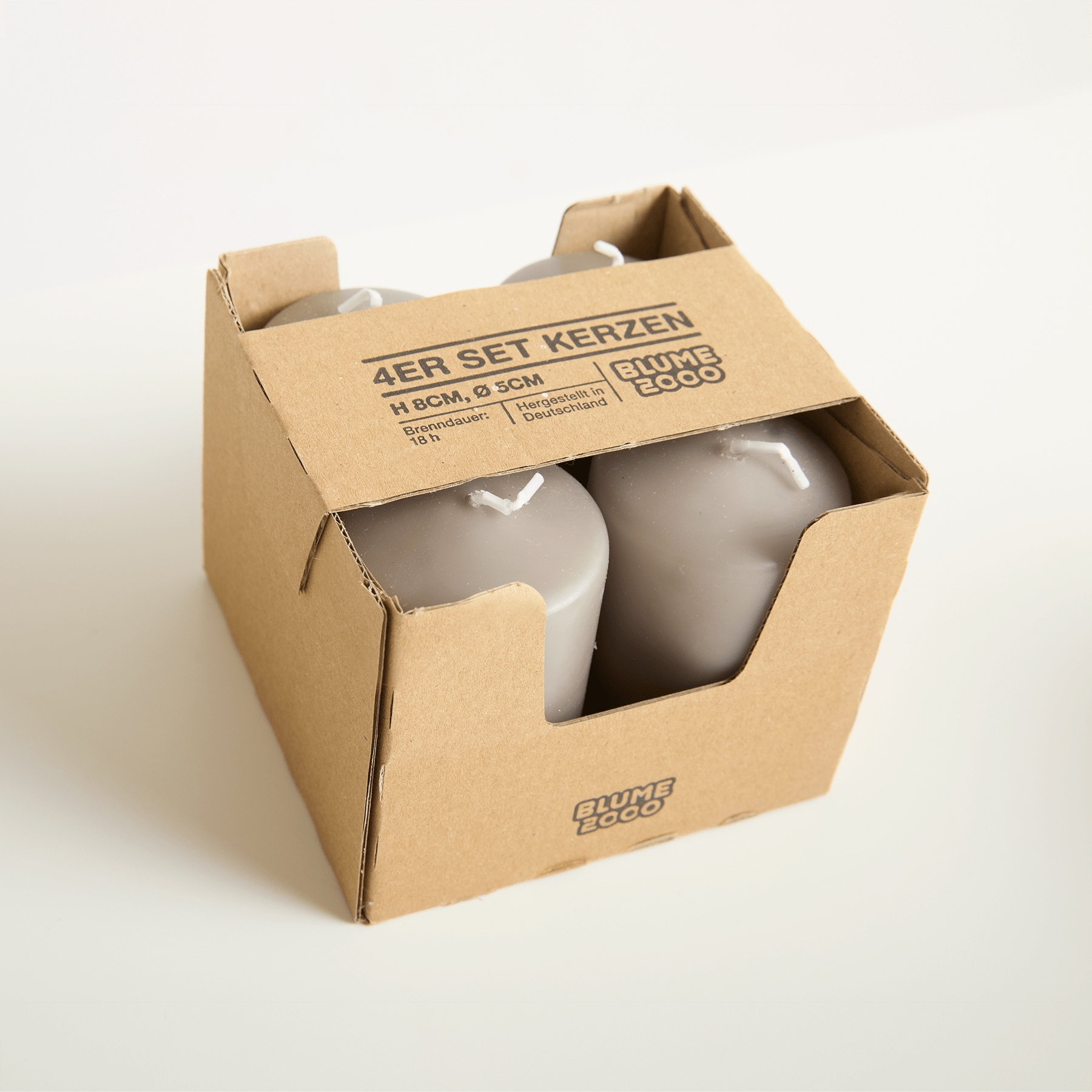 Ein Karton mit zwei Glasflaschen oder -behältern, auf dem der Text „AER SET KERZEN“ aufgedruckt ist.