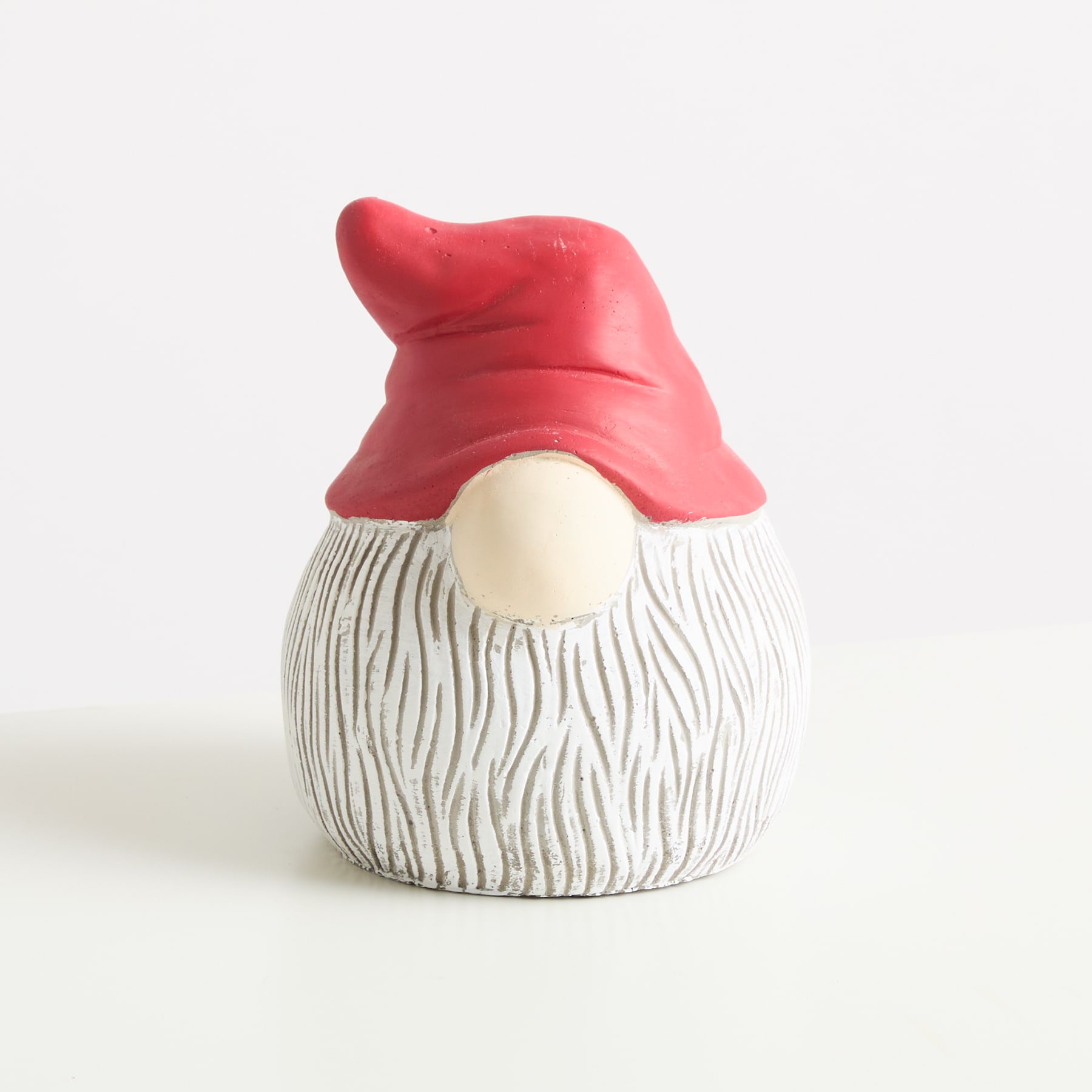 Eine kleine, runde Keramikfigur mit einem roten Hut und einem weißen, strukturierten Körper, der an eine Holzmaserung erinnert, sitzt auf einem schlichten weißen Hintergrund.