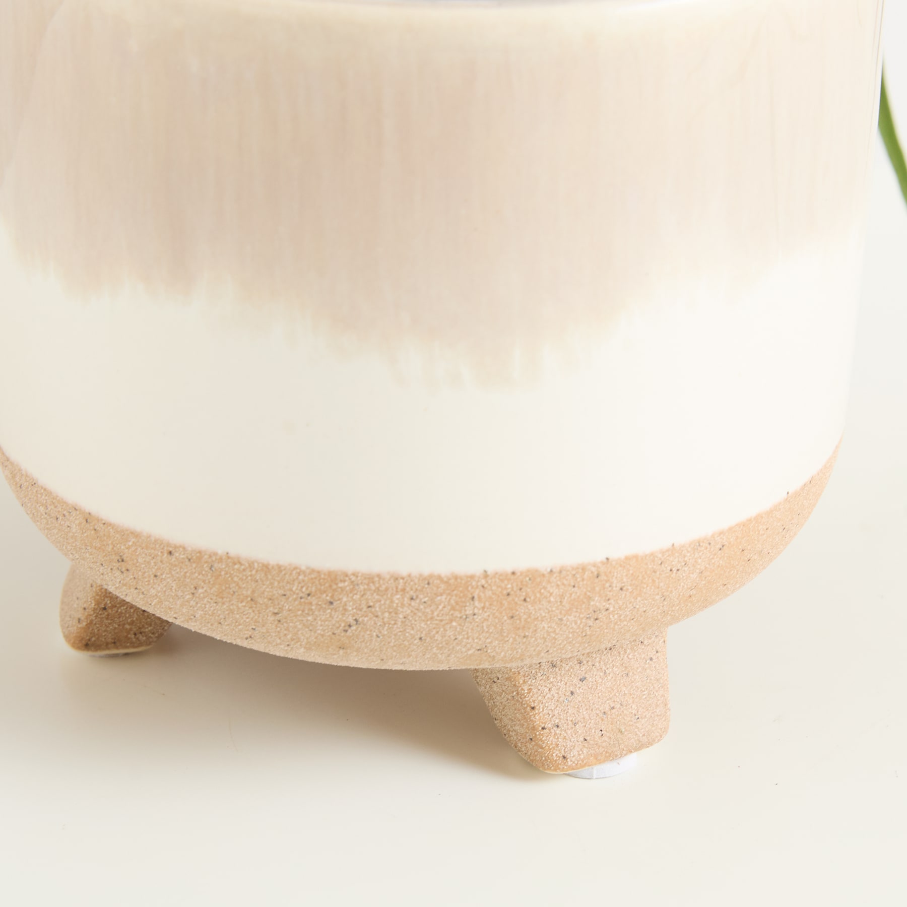 Eine weiße Keramikschale oder -vase ruht auf einem beigen, strukturierten Sockel und schafft so eine einfache und minimalistische Komposition vor einem schlichten Hintergrund.