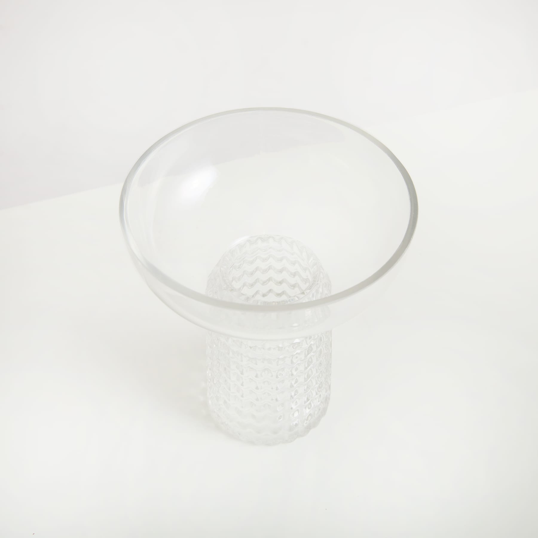 Eine klare Glasschale mit strukturiertem weißen Boden steht auf einem schlichten weißen Hintergrund.