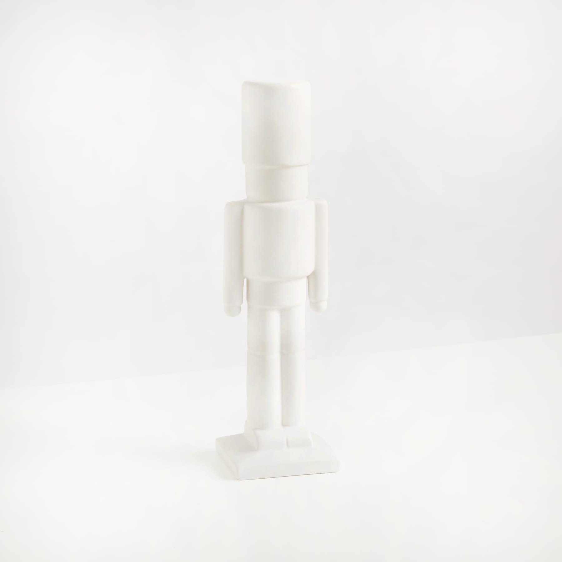 Eine einfache, minimalistische weiße Figur steht allein vor einem schlichten weißen Hintergrund.