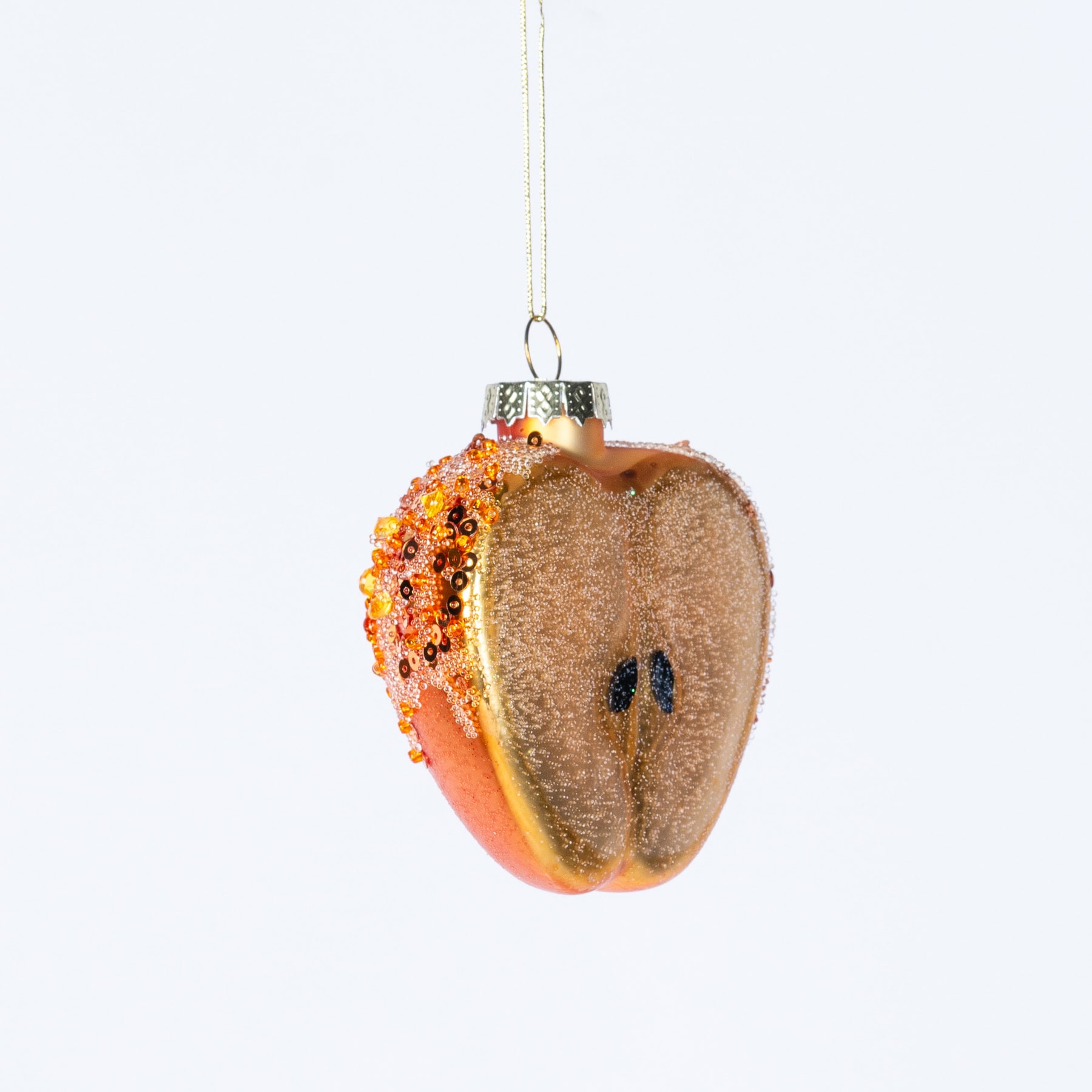 Ein Glasornament in Form einer Paprika mit strukturierter Oberfläche und leuchtenden Orange- und Gelbtönen hängt vor einem schlichten weißen Hintergrund.