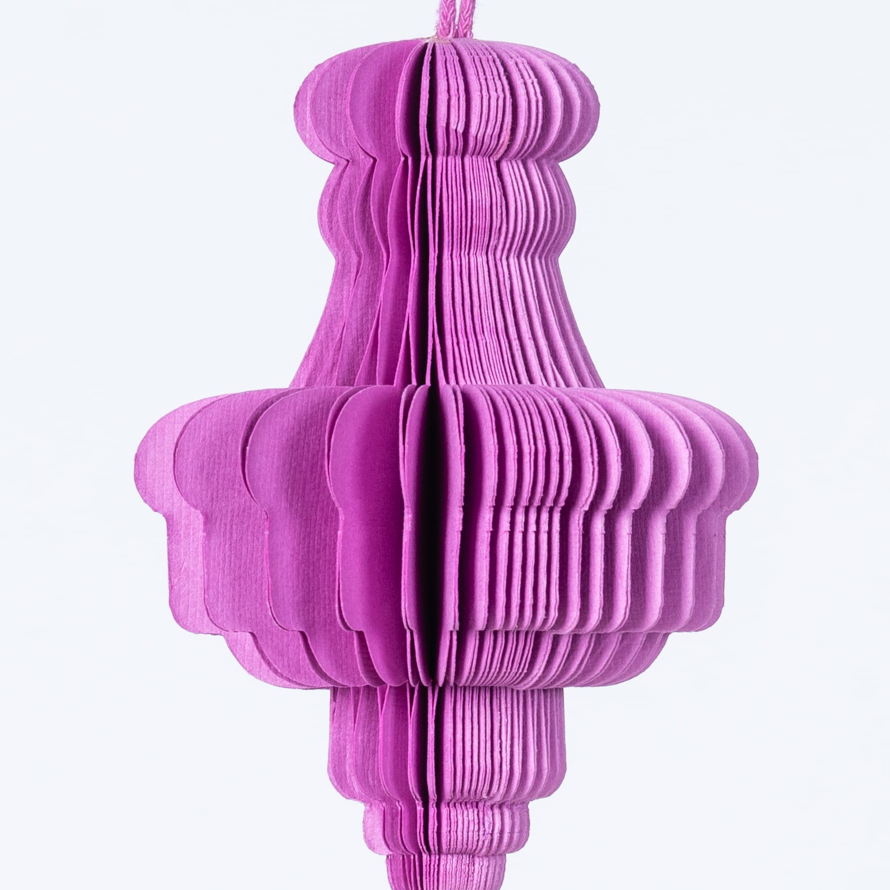 Eine lebendige, dreidimensionale Papierskulptur in einem auffälligen Rosaton, die vor einem schlichten weißen Hintergrund schwebt.