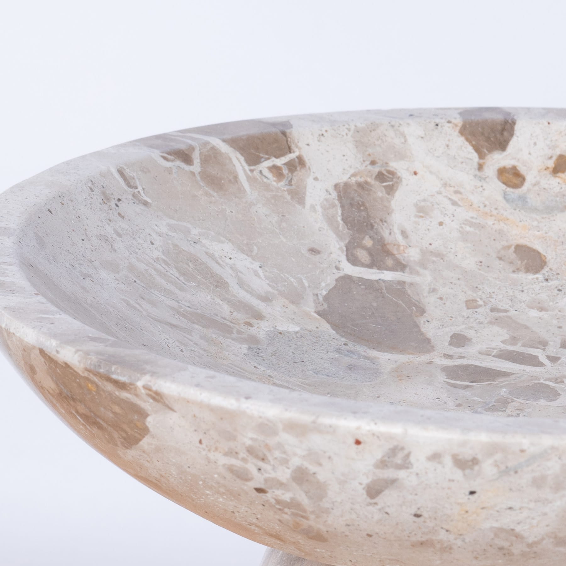 Eine flache, runde Schale aus Naturstein mit gesprenkelter, strukturierter Oberfläche und sichtbaren Variationen in Farbe und Muster.