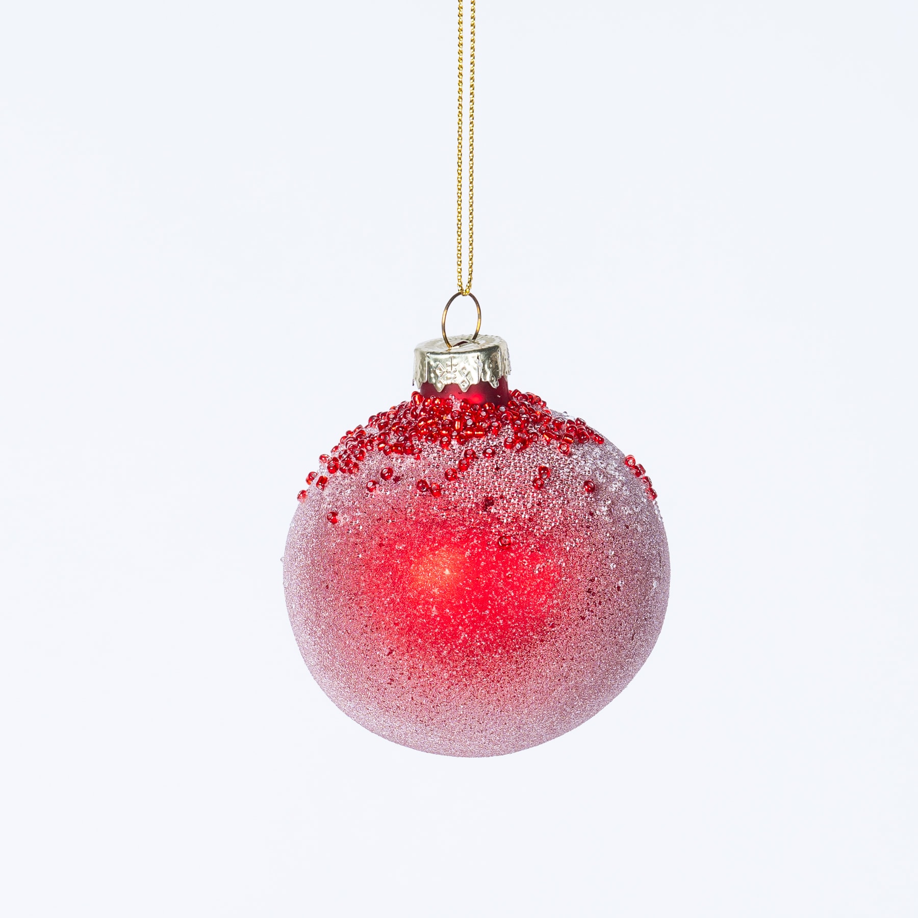 Ein rot-weiß glitzernder Weihnachtsschmuck hängt vor einem schlichten weißen Hintergrund.
