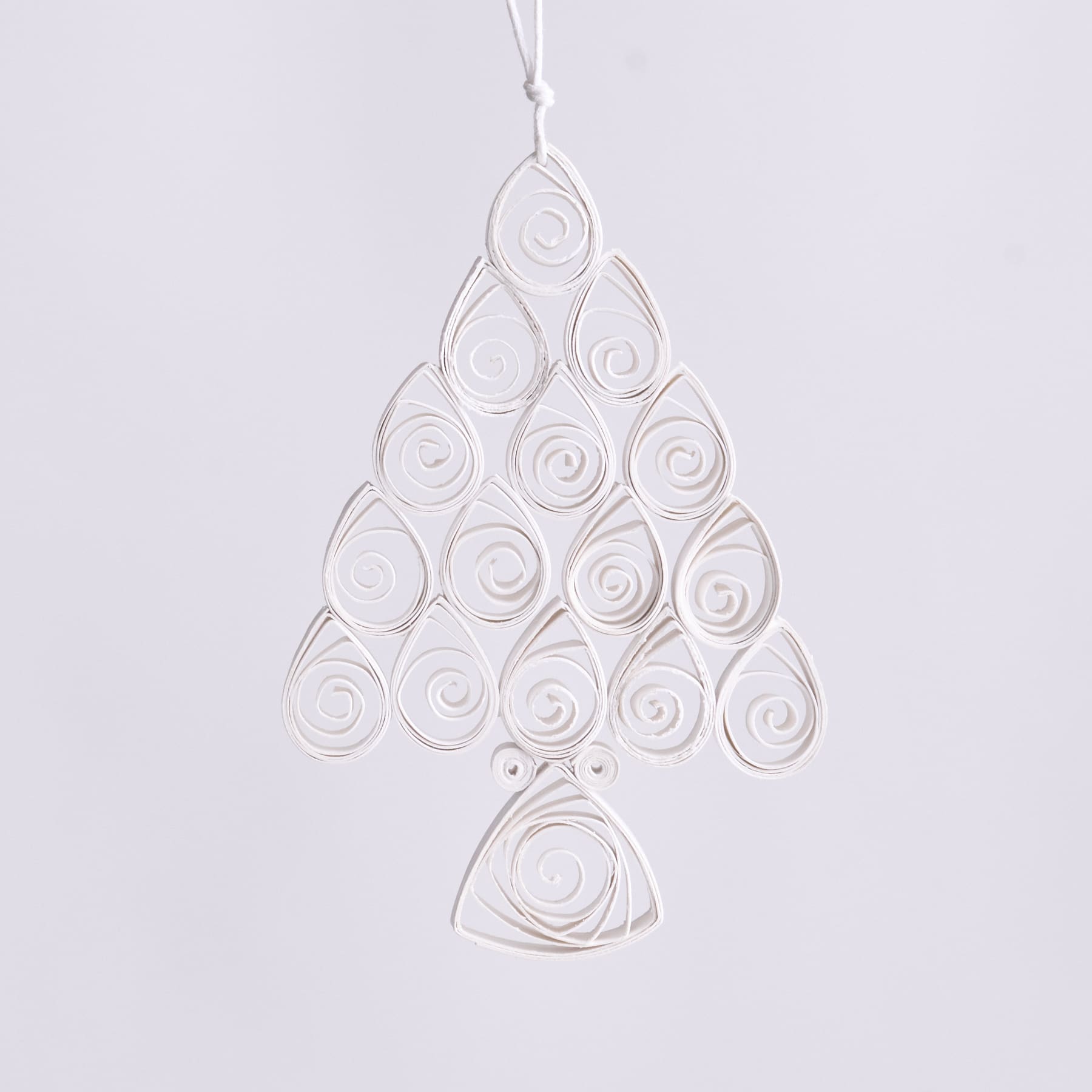 Ein zartes, weißes Papierschnittornament mit komplizierten Spiralmustern und einem zentralen symmetrischen Design, das vor einem schlichten, hellen Hintergrund schwebt.