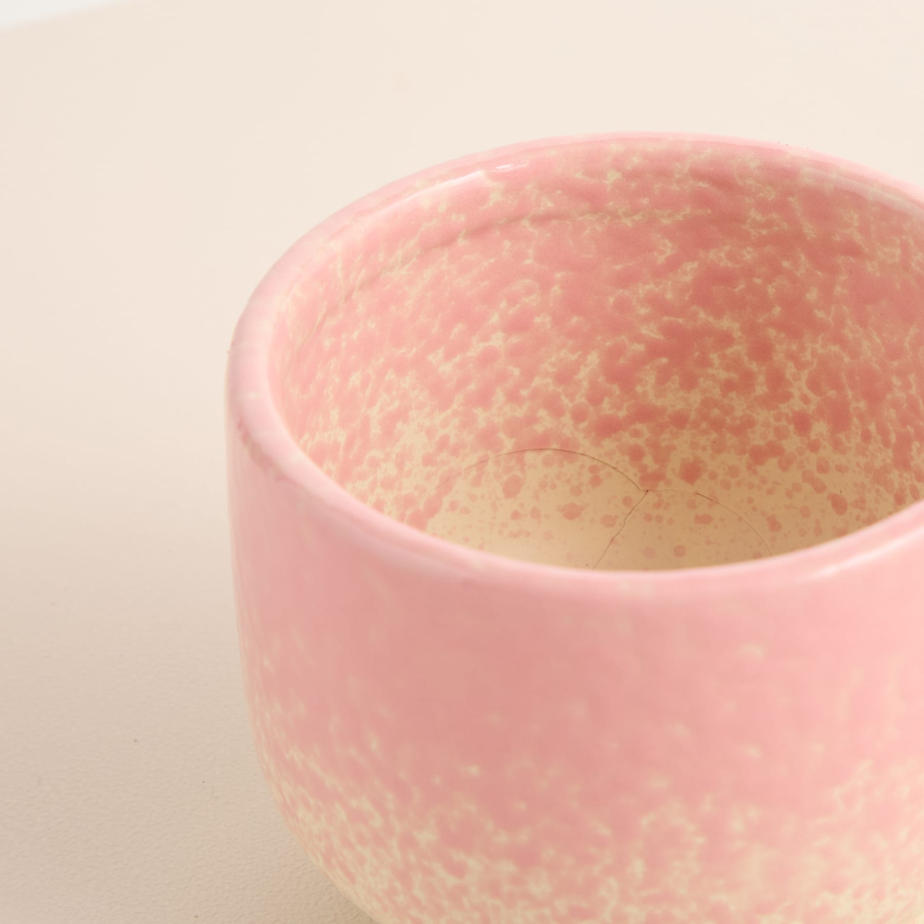Eine rosa Keramikschüssel mit strukturierter, gesprenkelter Innenfläche steht vor einem schlichten, hellen Hintergrund.