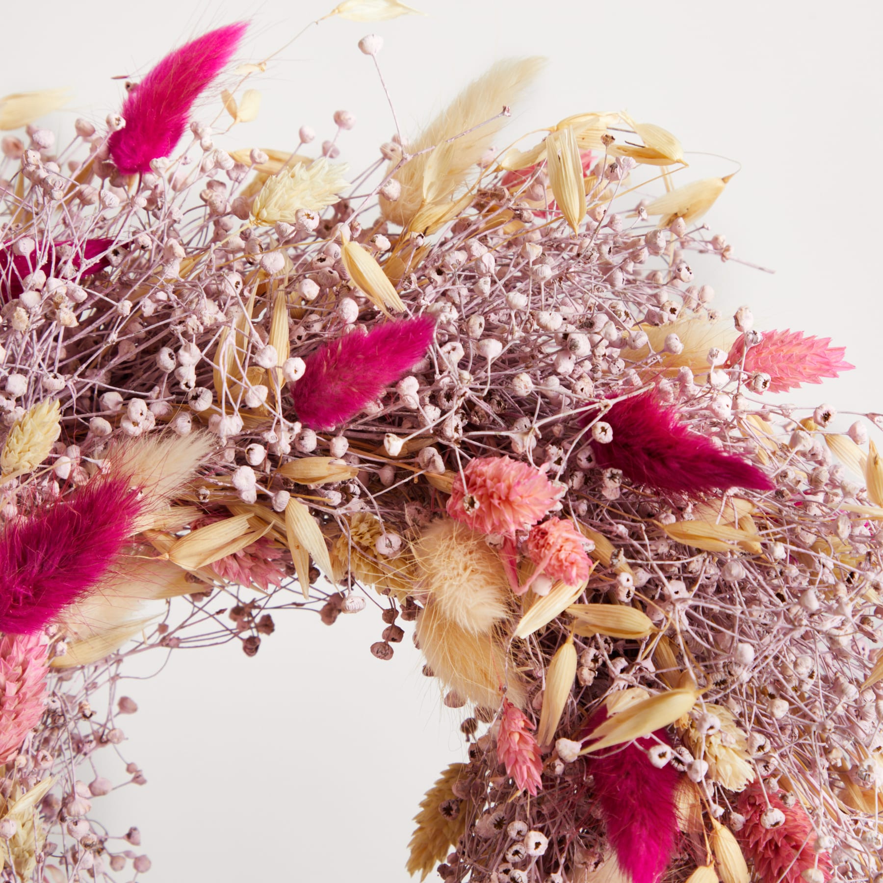 Ein lebendiges Arrangement aus getrockneten Blumen, Blättern und anderen natürlichen Elementen in Rosa-, Lila- und Goldtönen, das eine optisch beeindruckende und strukturierte Komposition ergibt.