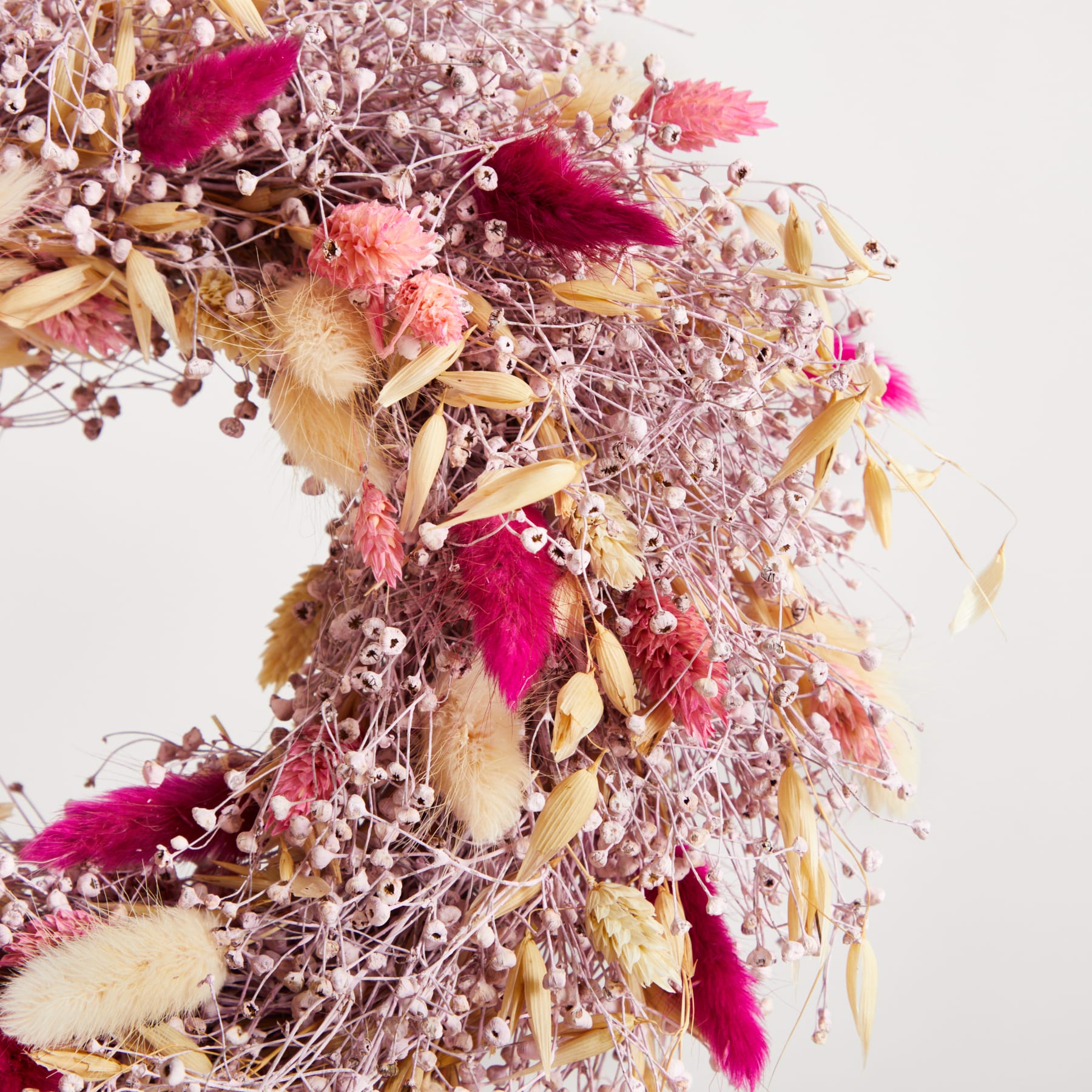 Ein lebendiges Arrangement aus getrockneten Blumen, Blättern und anderen natürlichen Elementen in Rosa-, Lila- und Beigetönen, das eine optisch beeindruckende und strukturierte Komposition ergibt.
