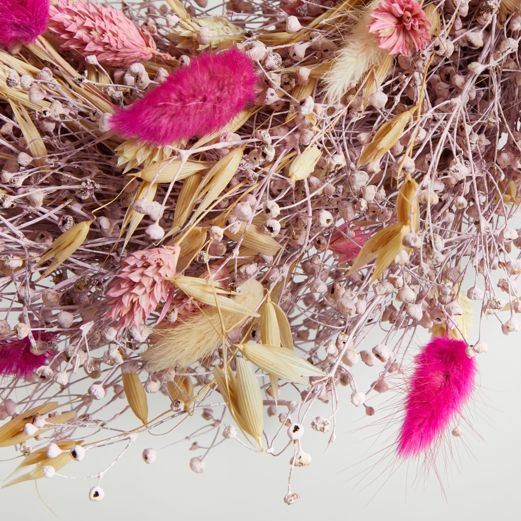 Ein lebendiges Arrangement aus getrockneten Blumen und Pflanzen, darunter rosa Federbüsche, Weizenhalme und andere natürliche Elemente, die eine optisch beeindruckende und strukturierte Komposition ergeben.