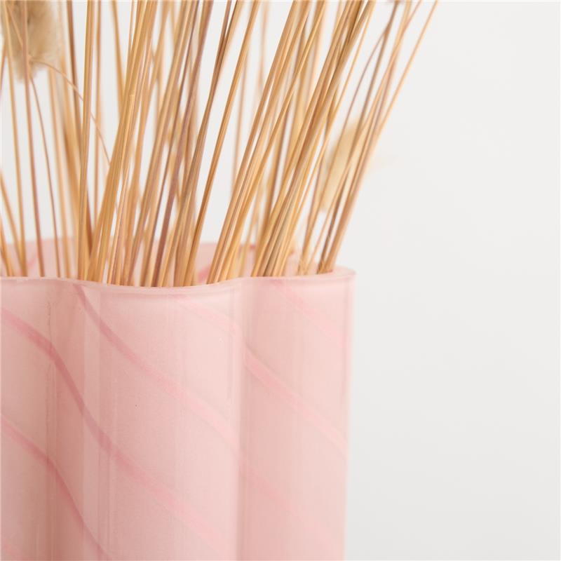 Ein Bündel Holzspieße oder Zahnstocher in einem rosa Behälter vor einem schlichten weißen Hintergrund.