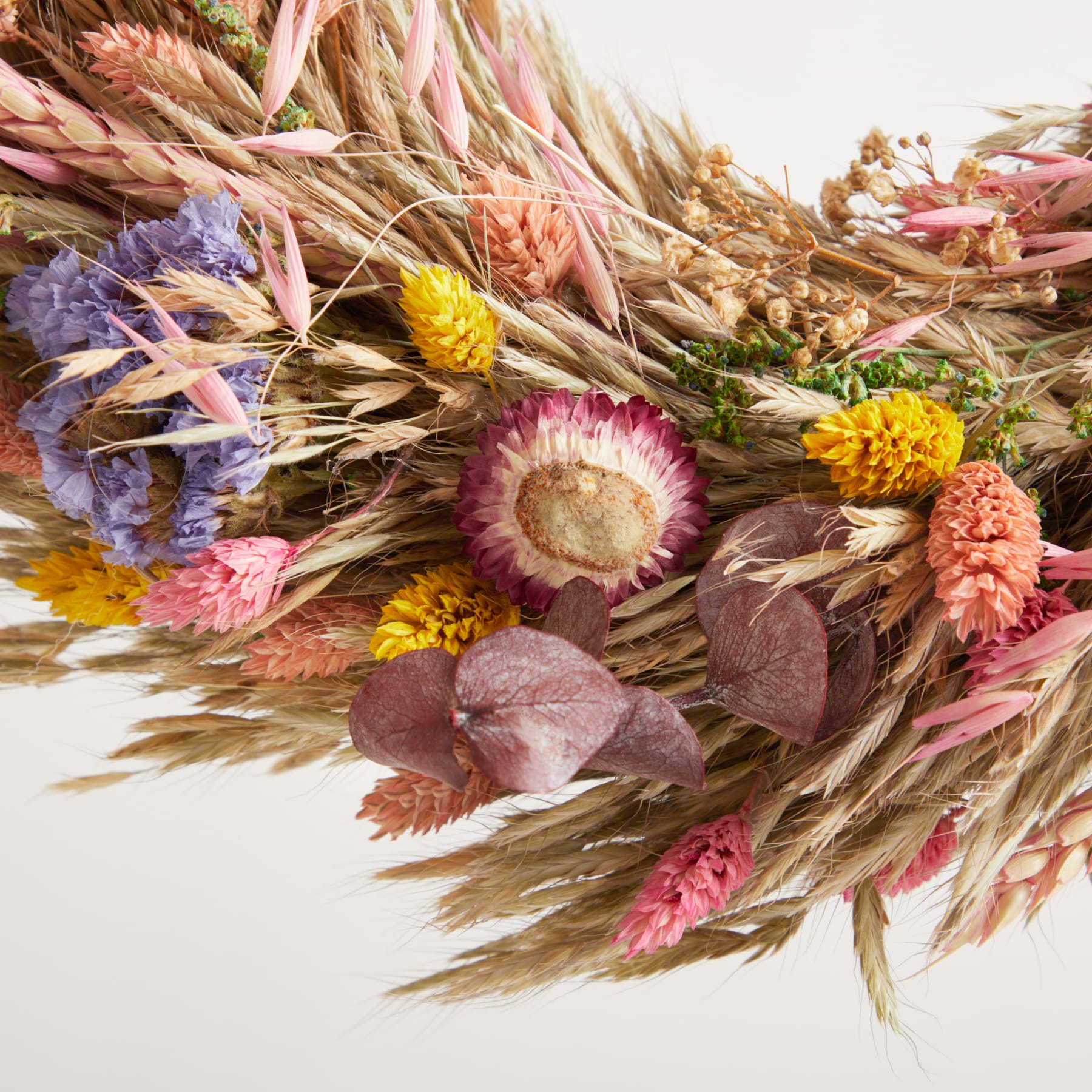 Ein lebendiger Strauß getrockneter Blumen, Gräser und Weizenhalme in warmen Herbsttönen, der ein rustikales und natürliches Arrangement ergibt.