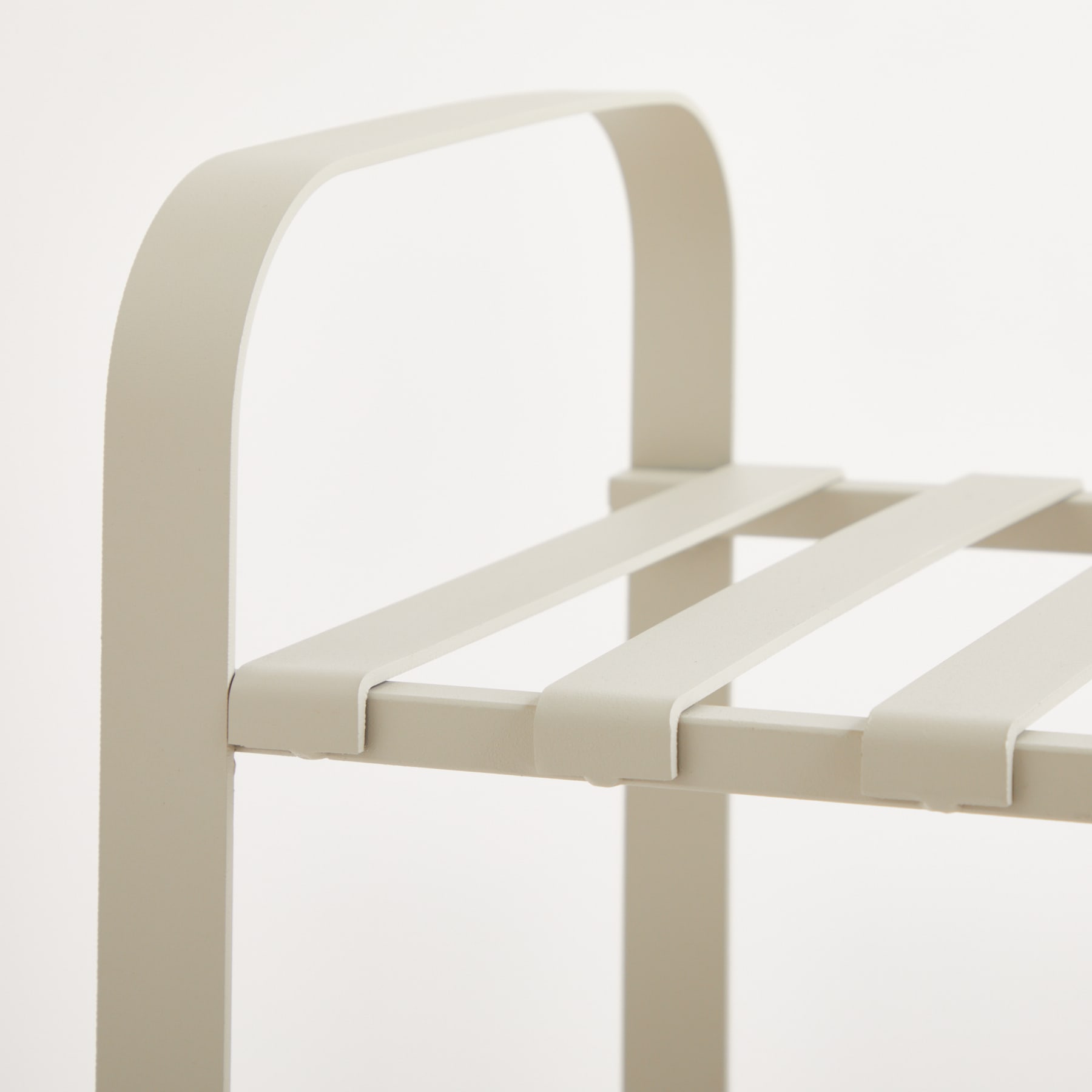Ein minimalistischer, weißer Metallstuhl mit geschwungener Rückenlehne und Lattensitzfläche vor einem schlichten, hellen Hintergrund.