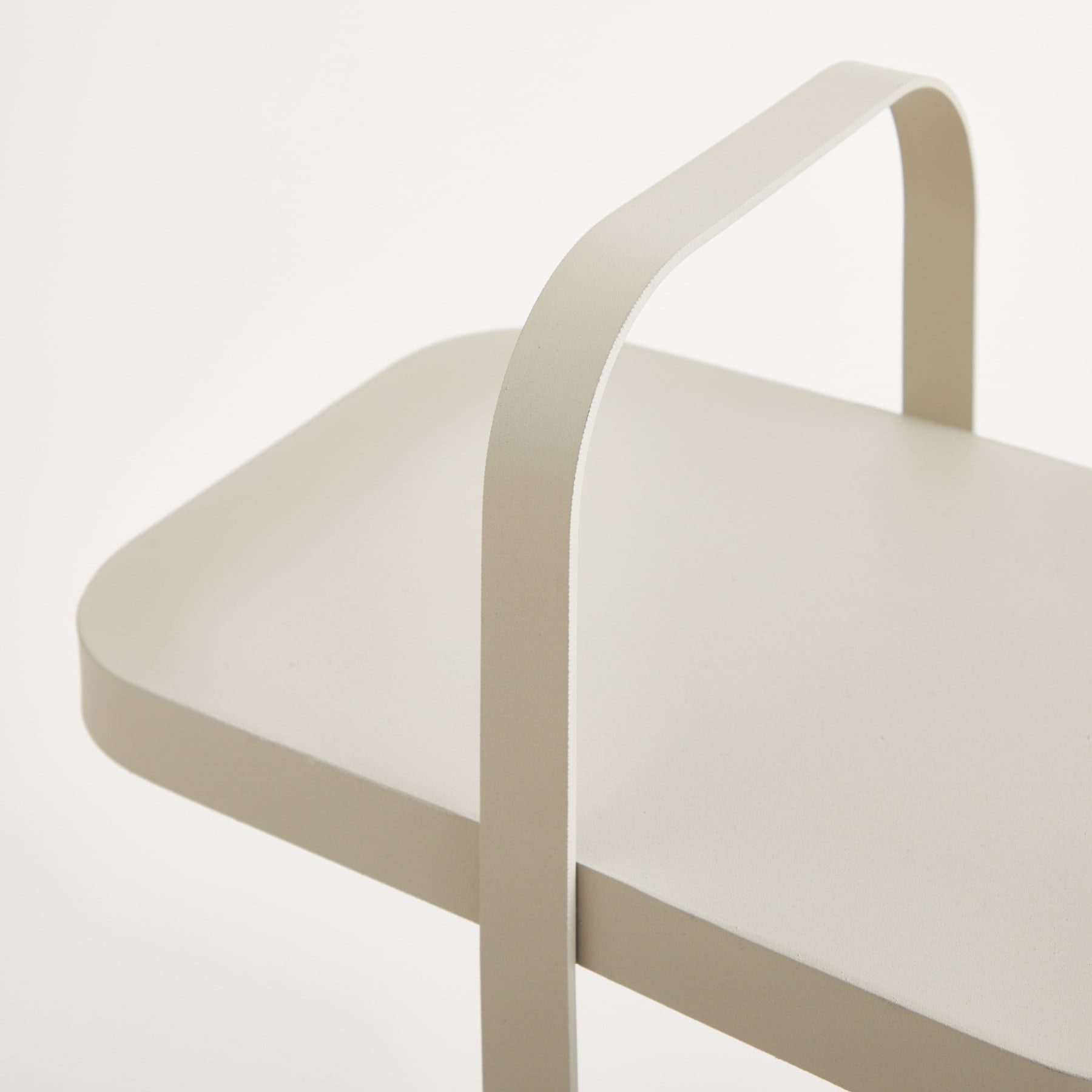 Ein einfaches, minimalistisches Design mit einem weißen, dreieckigen Objekt mit einem gebogenen Griff vor einem schlichten, hellen Hintergrund.