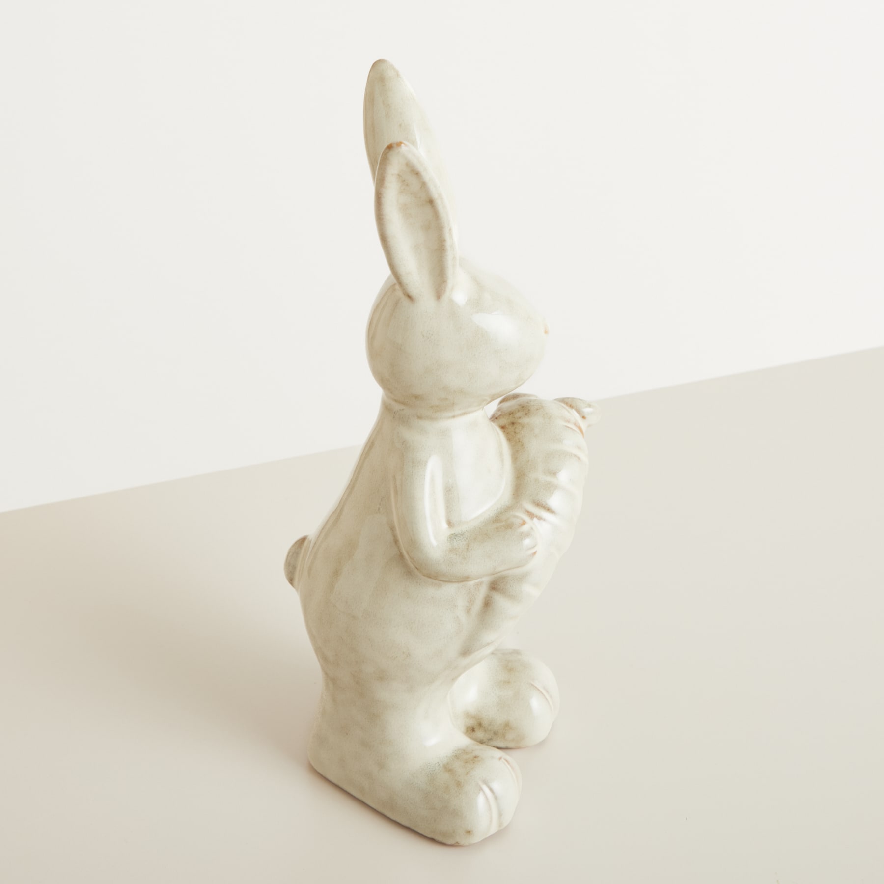Eine weiße Keramikfigur eines aufrecht stehenden Kaninchens mit einem einfachen, minimalistischen Hintergrund.