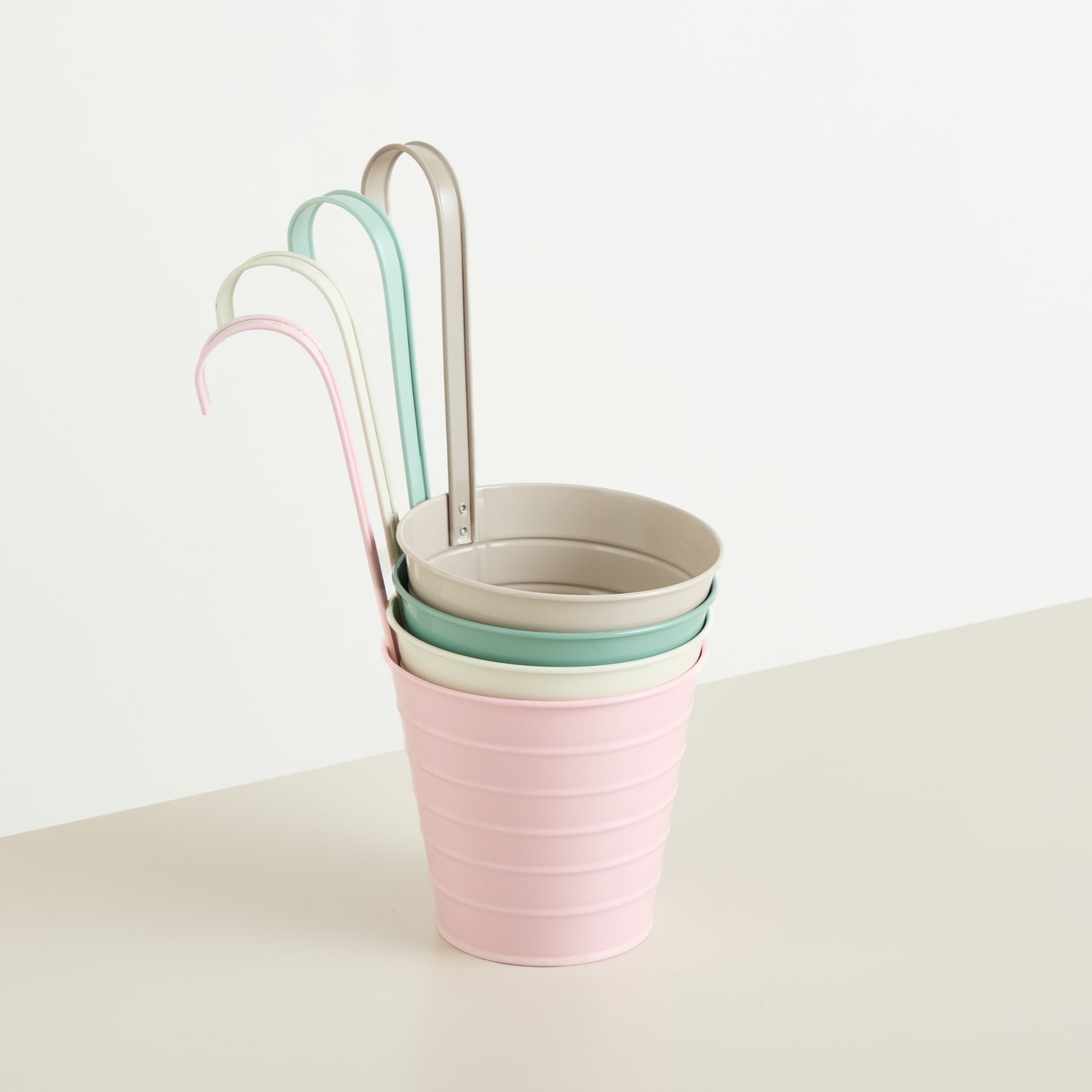 Ein Stapel bunter, ineinander verschachtelter Plastikbecher in Pastelltönen aus Rosa, Mint und Beige vor einem schlichten, hellen Hintergrund.