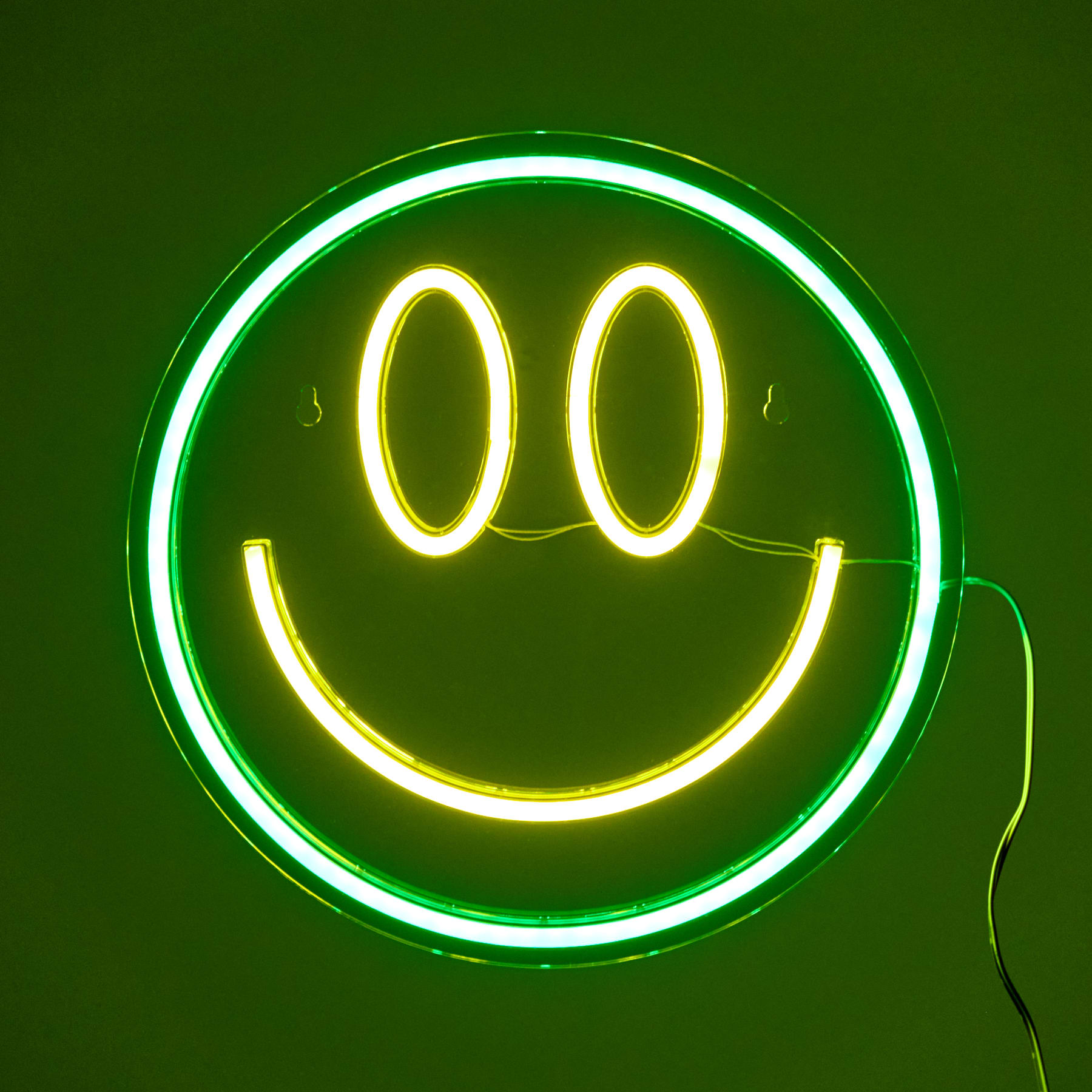 Ein leuchtendes Neon-Smiley-Symbol vor einem dunkelgrünen Hintergrund.