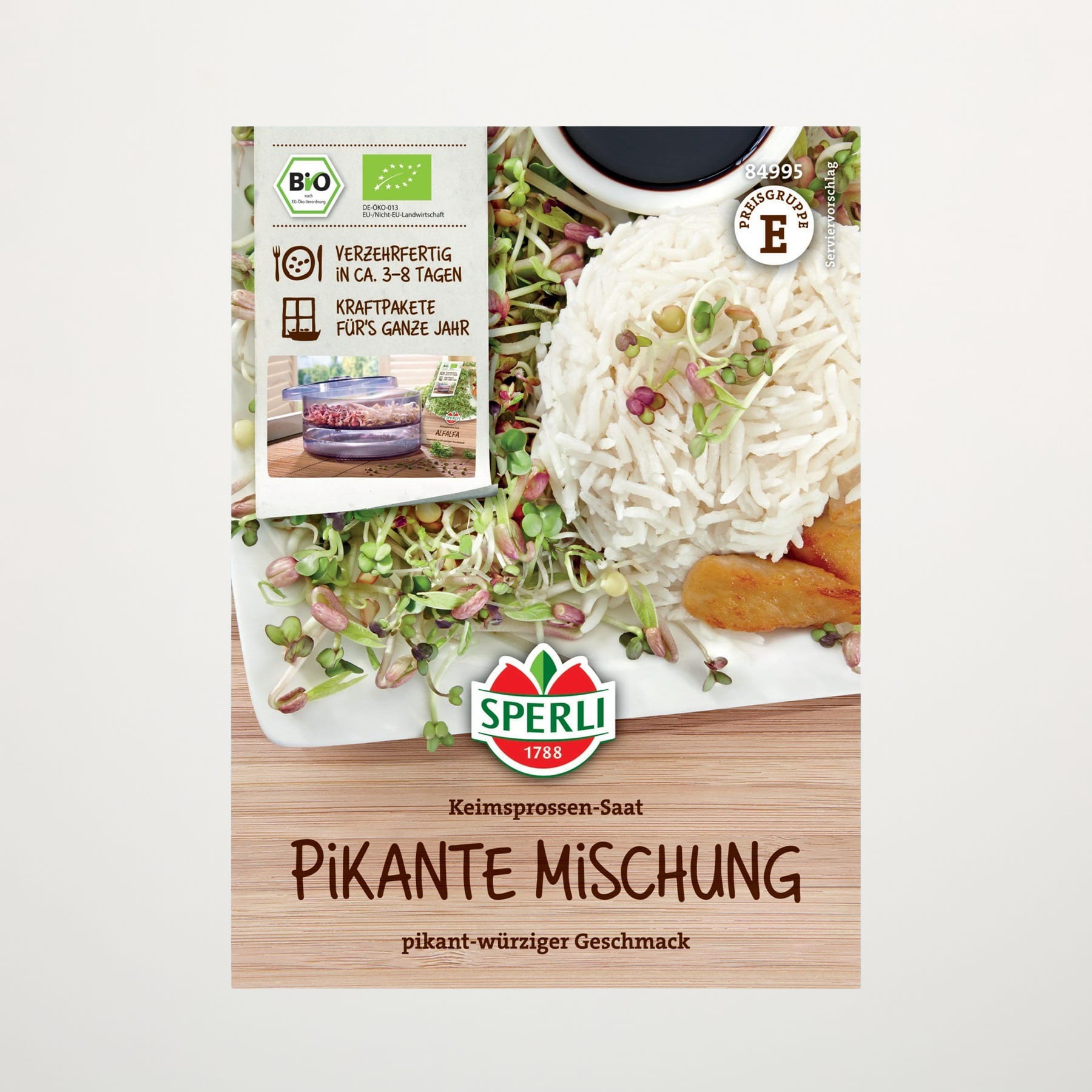 Auf dem Bild ist eine Holzkiste zu sehen, in der sich verschiedene Lebensmittel befinden, darunter eine Packung Bio-Sprossen, ein Glas Pfefferkörner und ein Etikett für ein Produkt der „Pikante Mischung“.