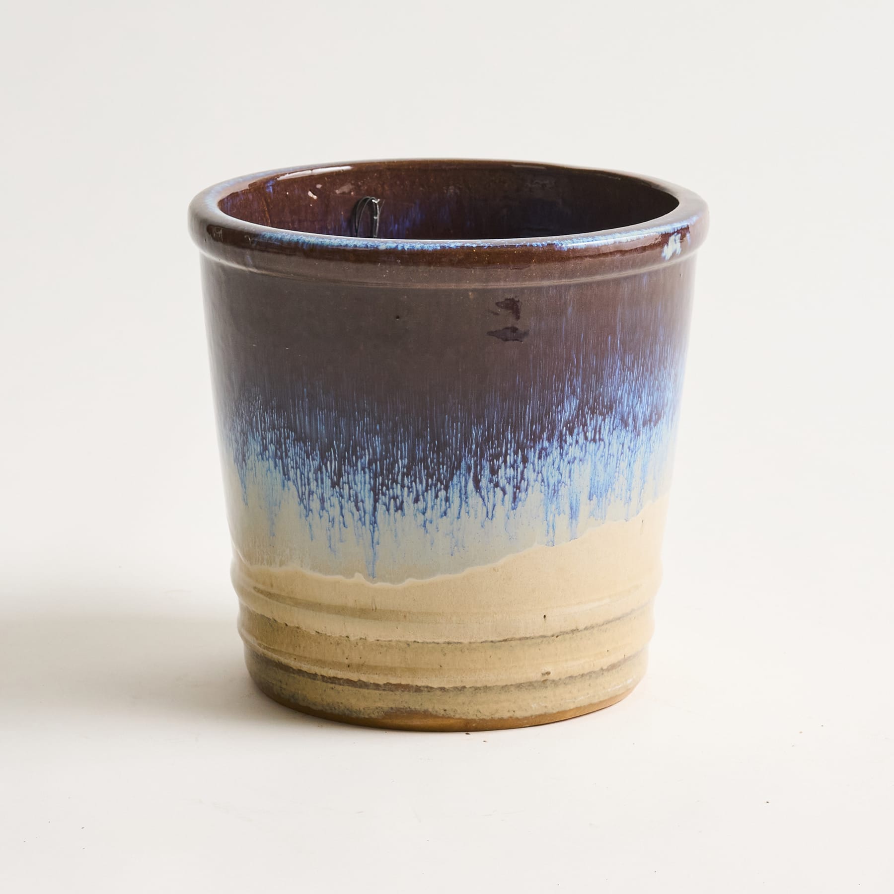 Eine Keramiktasse oder ein Keramikbecher mit einem unverwechselbaren Glasurmuster in Braun-, Blau- und Beigetönen.