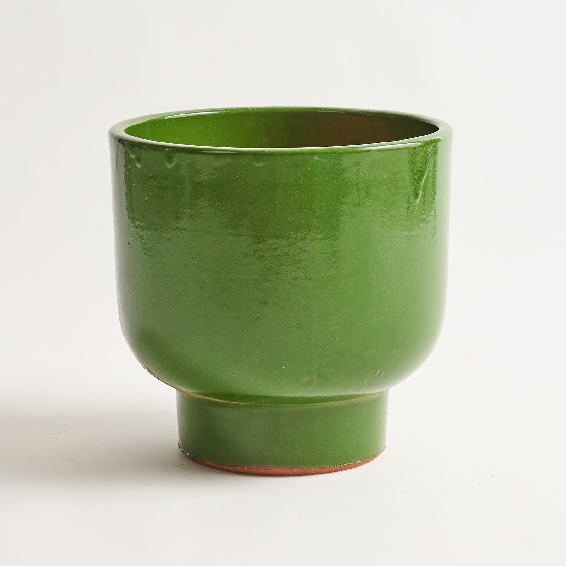 Eine leuchtend grüne Keramikschüssel oder -tasse mit einfachem, minimalistischem Design steht auf einem schlichten weißen Hintergrund.