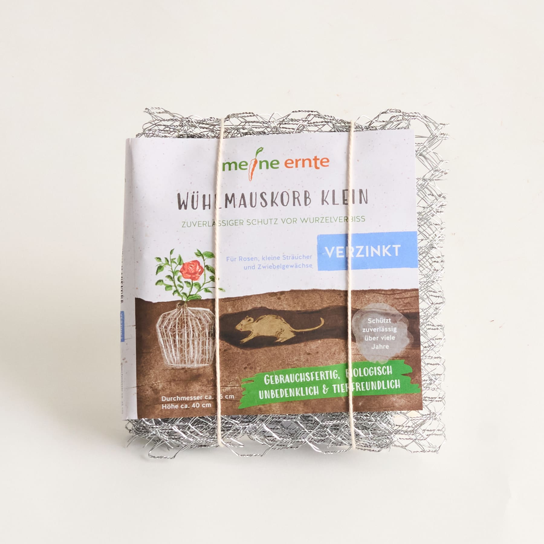 Das Bild zeigt einen kleinen Drahtkorb mit der Aufschrift „Wühlmauskorb klein“. Im Hintergrund sind eine Pflanze und Wurzeln zu sehen, was darauf hinweist, dass es sich um ein Produkt zum Schutz von Pflanzen vor Maulwurfsschäden handelt.