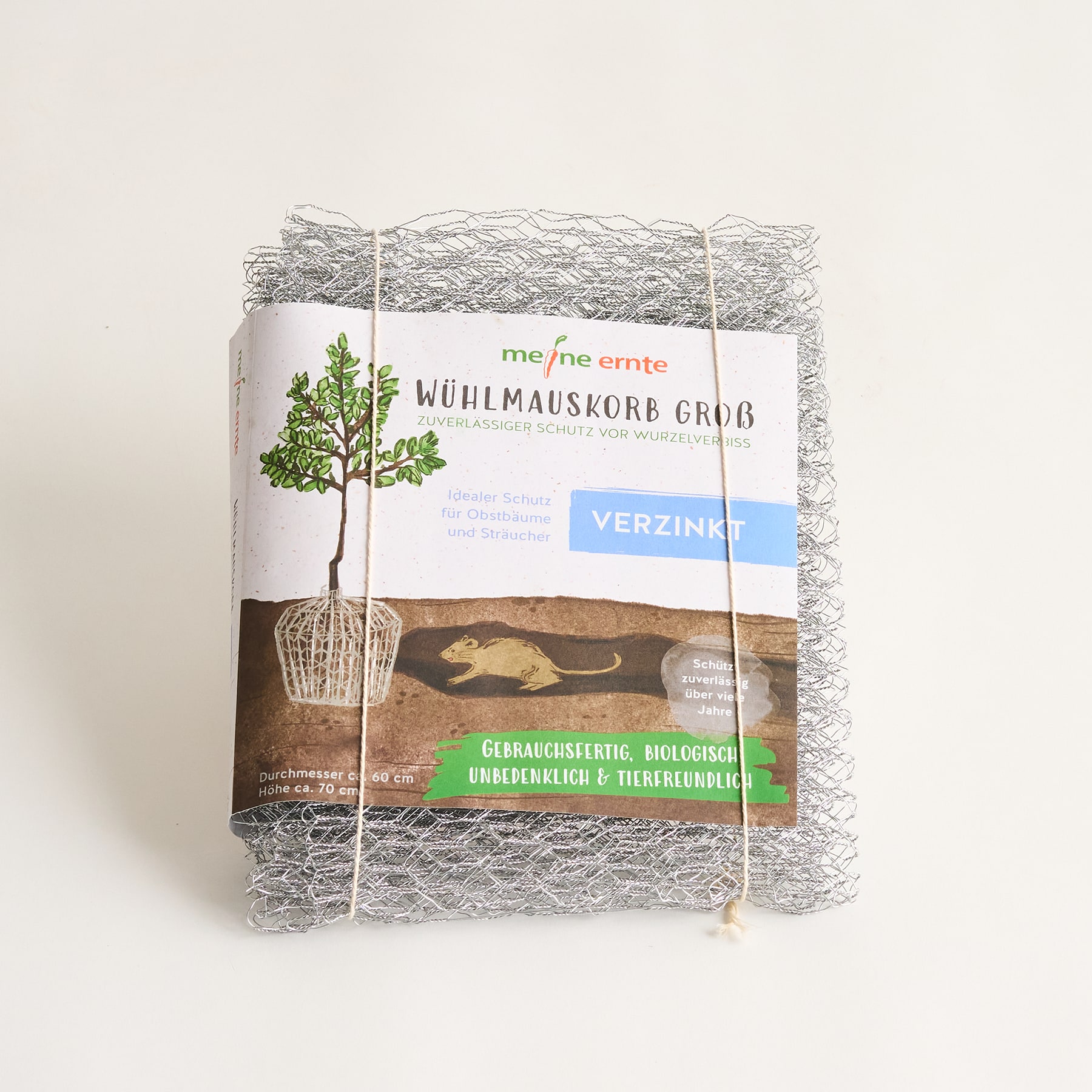 Das Bild zeigt einen Baumschutz oder Pflanzkübel aus Drahtgeflecht, in dem ein kleiner Baum oder eine Pflanze wächst, umgeben von einem gras- und erdbedeckten Hintergrund.