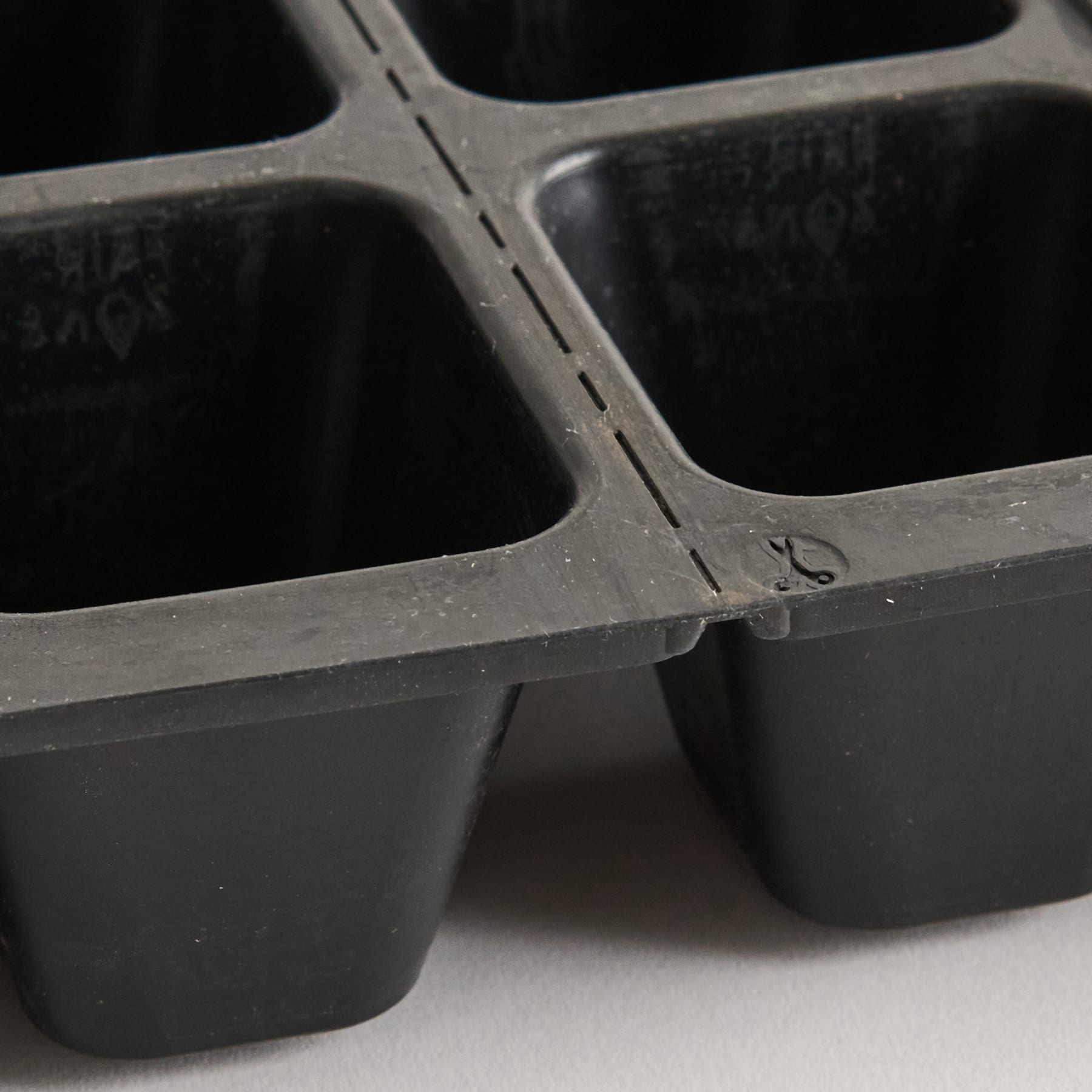 Ein schwarzer Plastikbehälter mit mehreren Fächern, der auf einer Oberfläche steht.