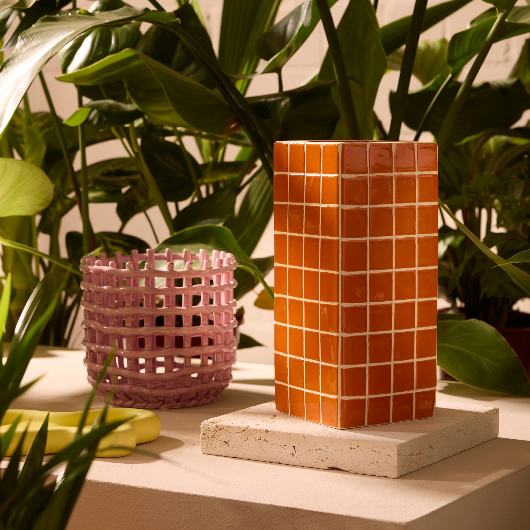 Ein quadratischer orangefarbener Behälter mit einem gitterartigen Muster auf der Oberfläche vor einem schlichten weißen Hintergrund.