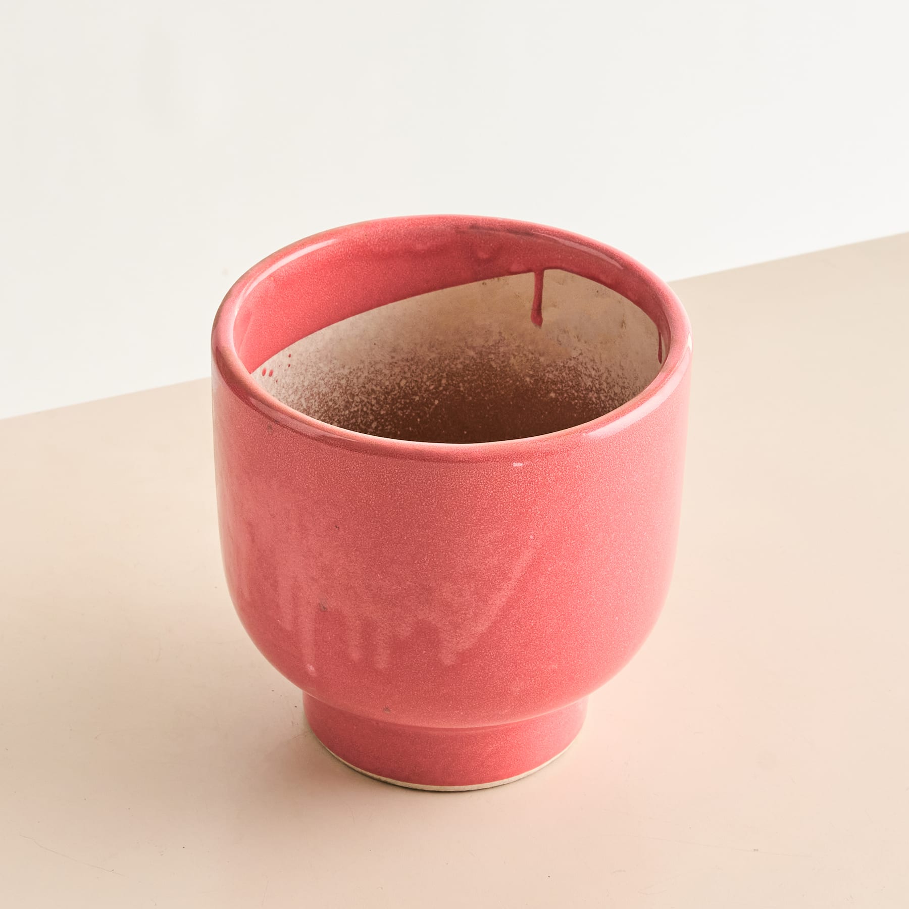 Eine leuchtend rote Keramiktasse, gefüllt mit einer dunklen, reichhaltigen Substanz, steht auf einer hellen Oberfläche.