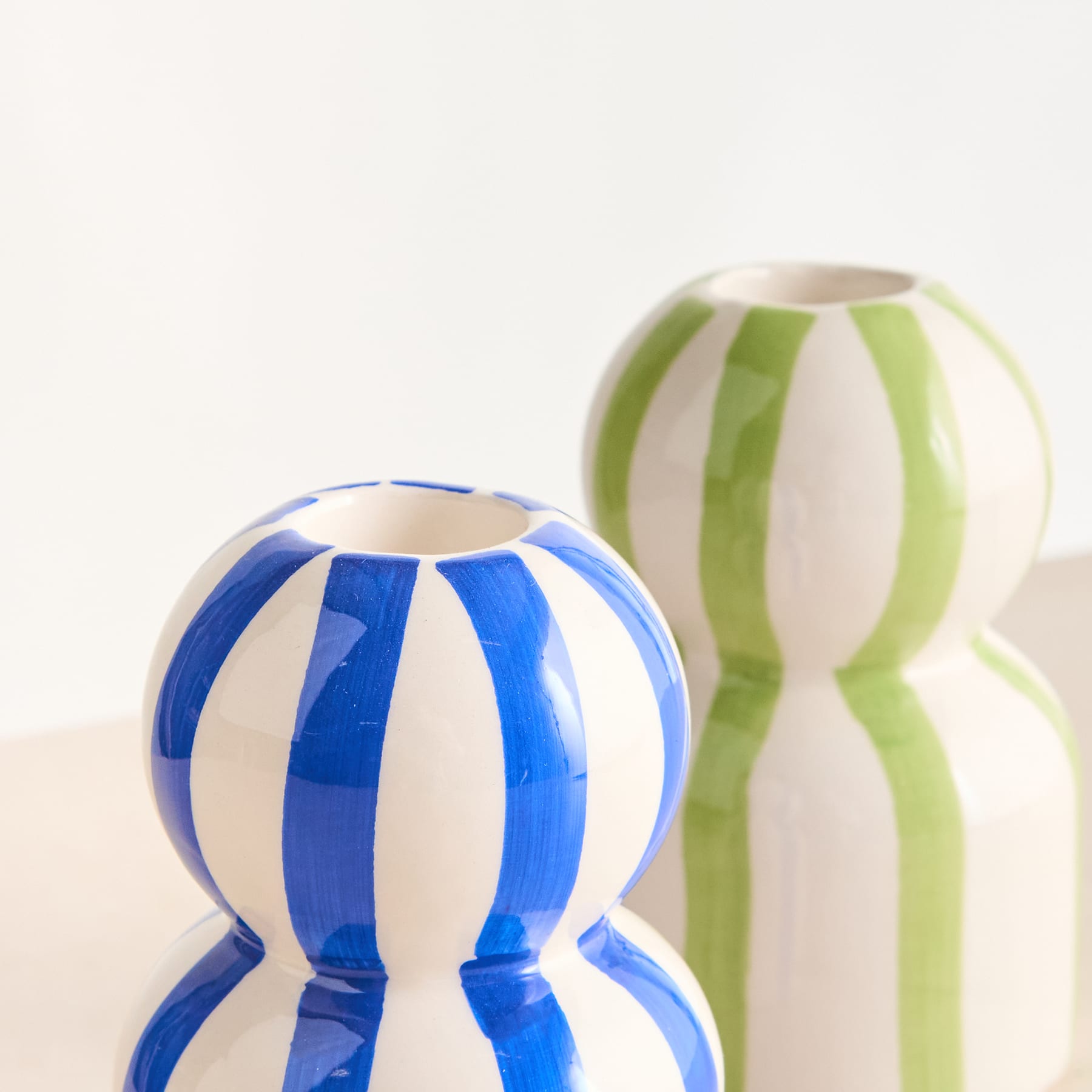 Zwei bunte Keramikvasen mit Streifenmuster in Blau und Grün auf schlichtem weißem Hintergrund.
