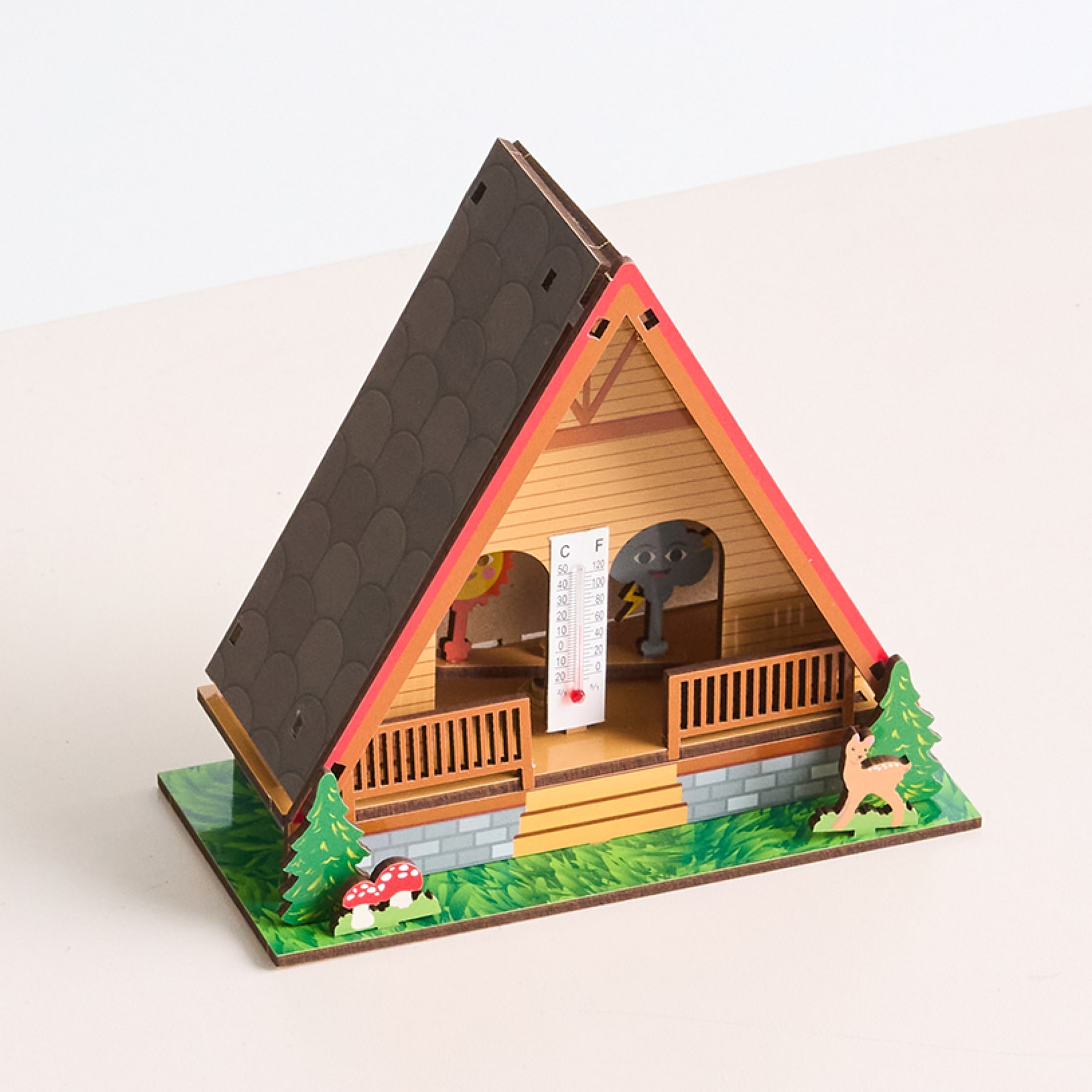 Auf einem schlichten, hellen Untergrund steht eine kleine A-förmige Holzhütte mit Balkon und grünem Gras drumherum.