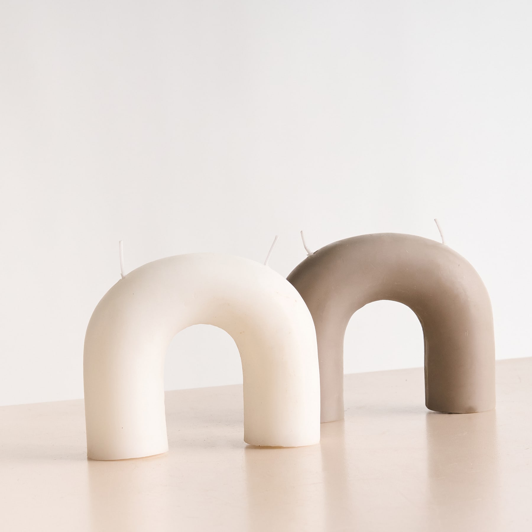 Zwei abstrakte, gewölbte Formen in einer neutralen, minimalistischen Umgebung.