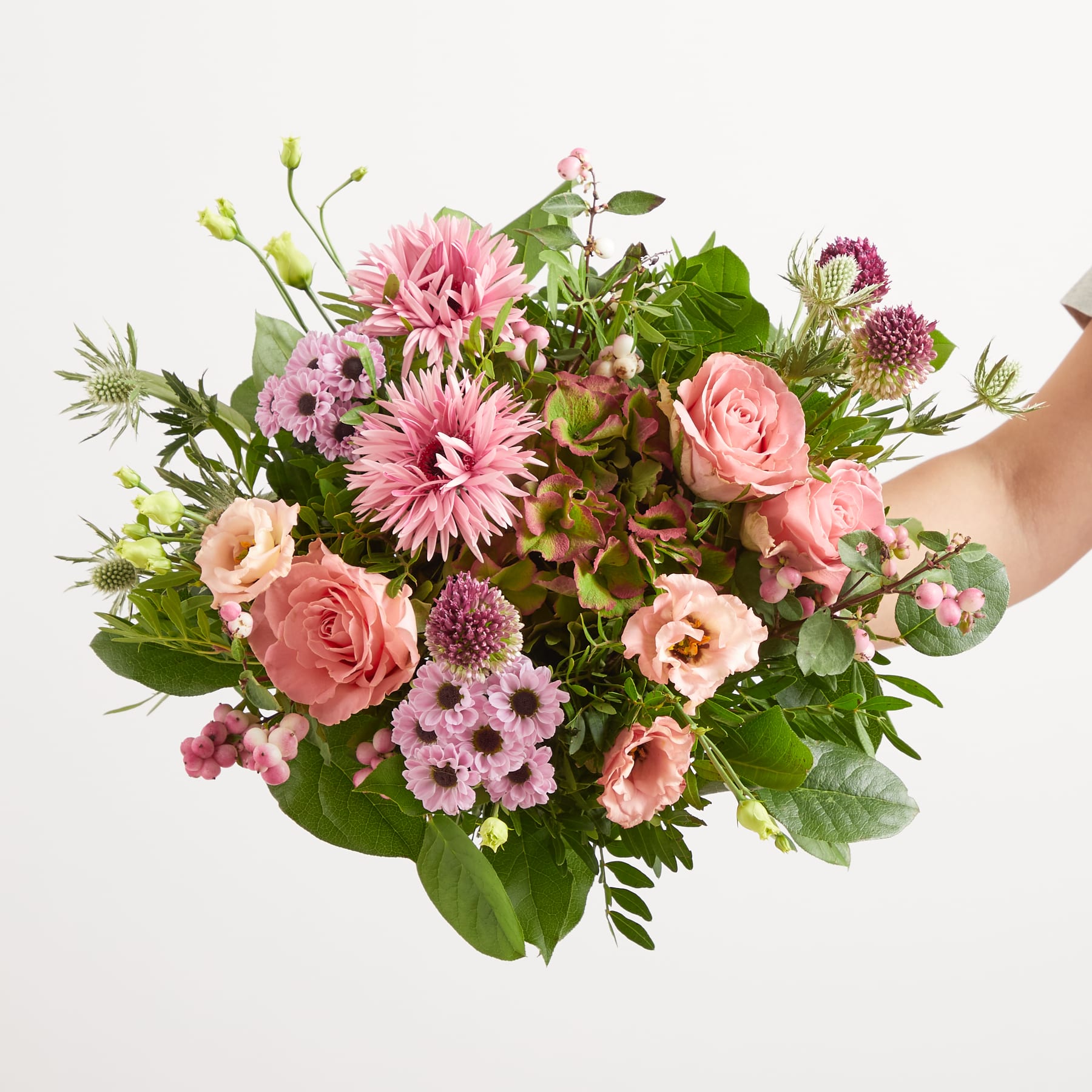 Ein leuchtender Strauß rosa und grüner Blumen, darunter Rosen, Gänseblümchen und andere üppige Blüten, füllt den Rahmen vor einem schlichten weißen Hintergrund.