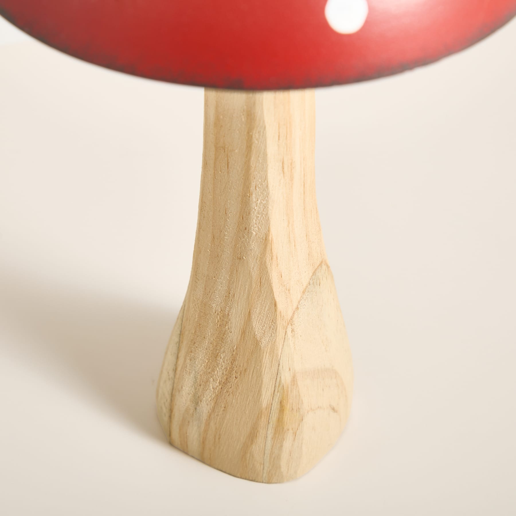 Eine rote, pilzförmige Lampe mit Holzsockel steht auf einem schlichten weißen Hintergrund.