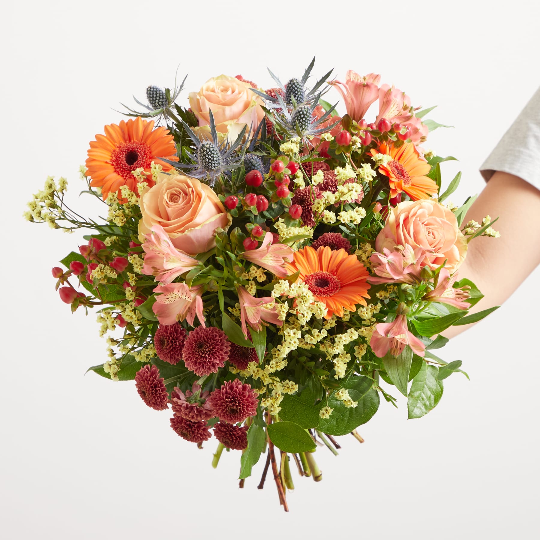 Ein farbenfroher Strauß verschiedener Blumen, darunter Rosen, Gerbera und andere bunte Blüten, üppig und optisch ansprechend vor einem schlichten weißen Hintergrund arrangiert.