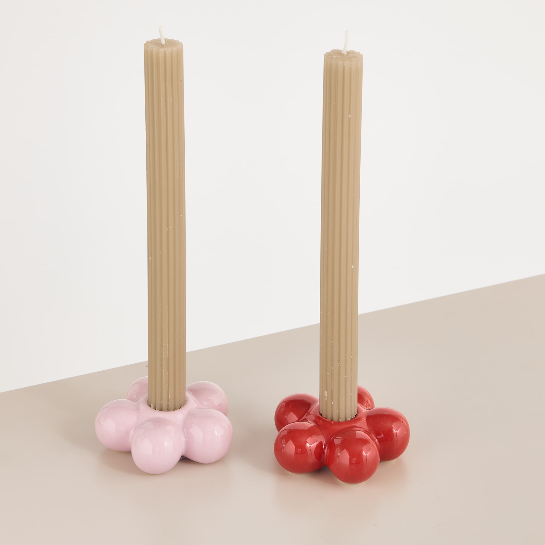 Zwei Holzdübel stehen aufrecht, an deren Basis sich Ansammlungen rosa und roter kugelförmiger Objekte auf einer hellen Oberfläche befinden.