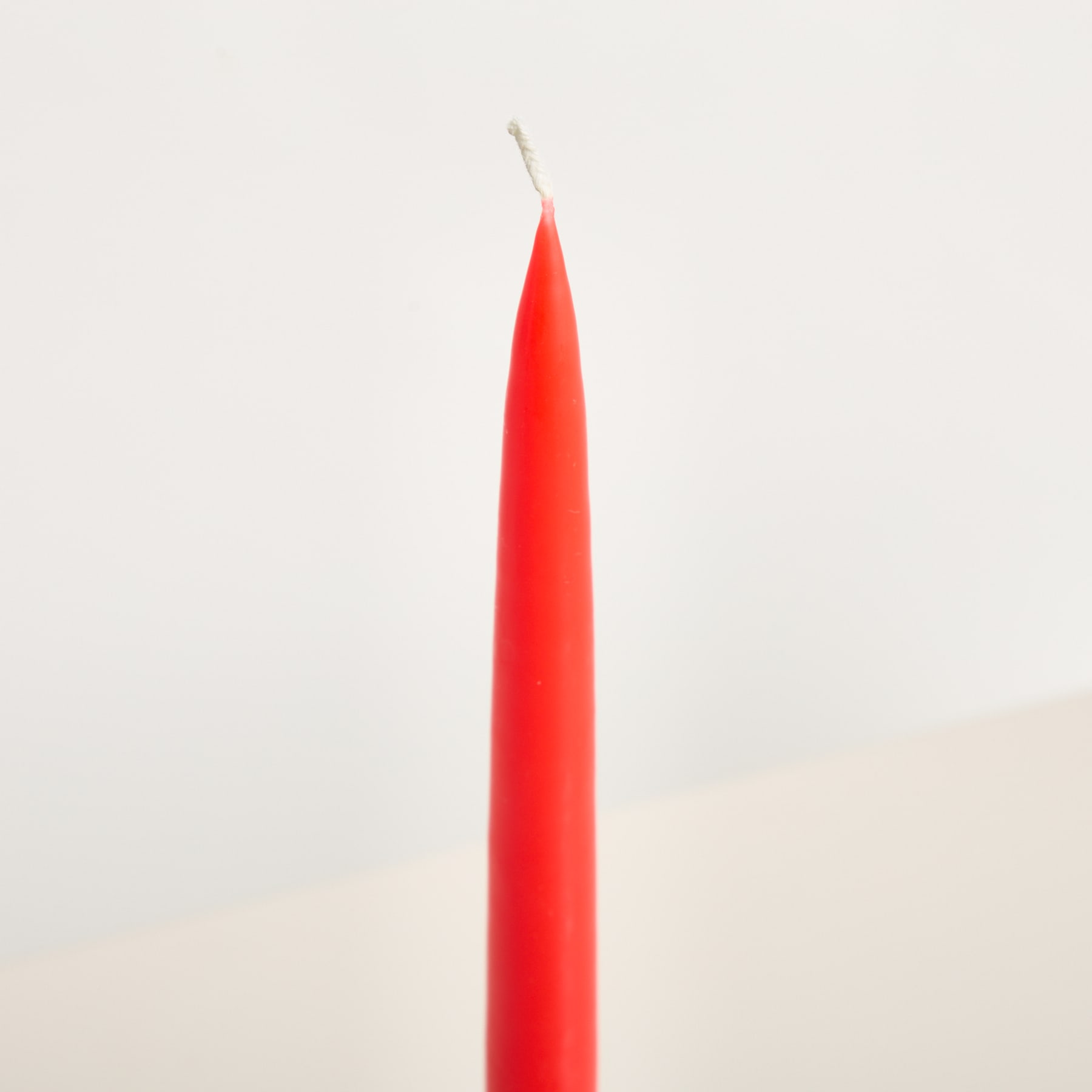 Ein leuchtend roter Stift liegt diagonal vor einem schlichten, cremefarbenen Hintergrund.