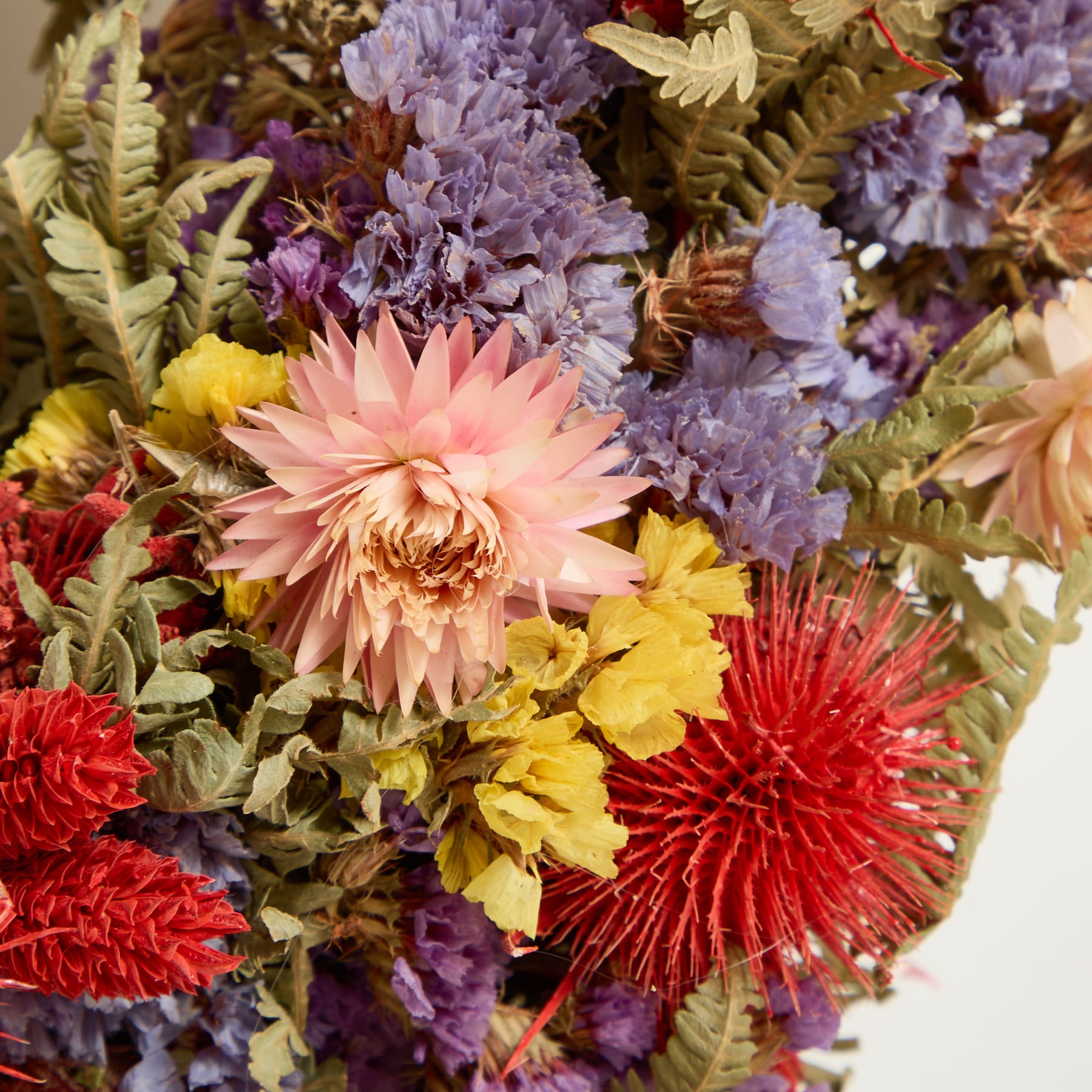 Ein lebendiger und farbenfroher Blumenkranz aus verschiedenen Blüten, darunter rote, gelbe und violette Blumen, füllt den Rahmen und schafft eine optisch beeindruckende und fesselnde Darstellung.