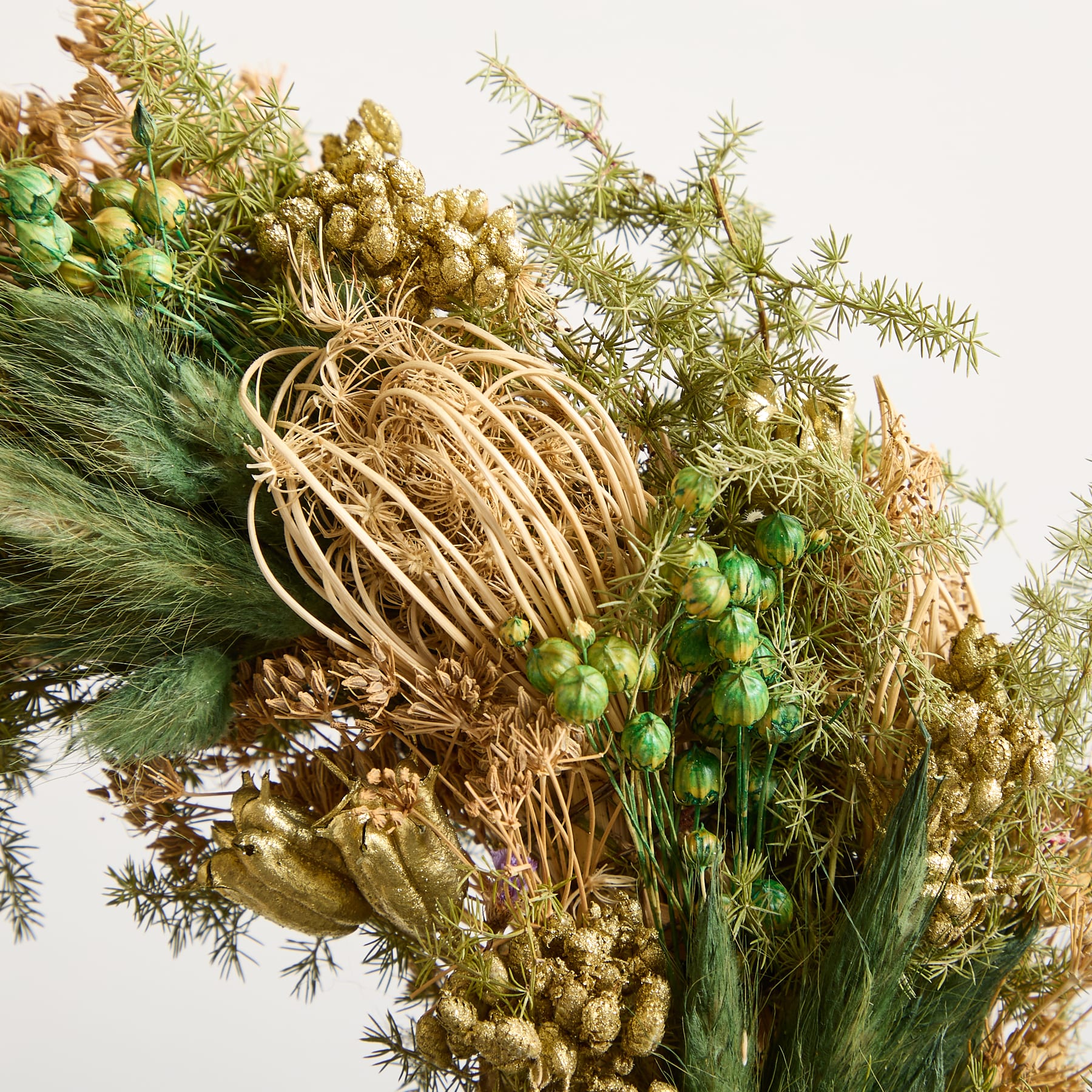 Ein lebendiges und strukturiertes Arrangement verschiedener getrockneter und natürlicher Elemente, darunter Kiefernzweige, getrocknete Blumen und andere organische Materialien, die eine optisch beeindruckende und erdige Komposition schaffen.
